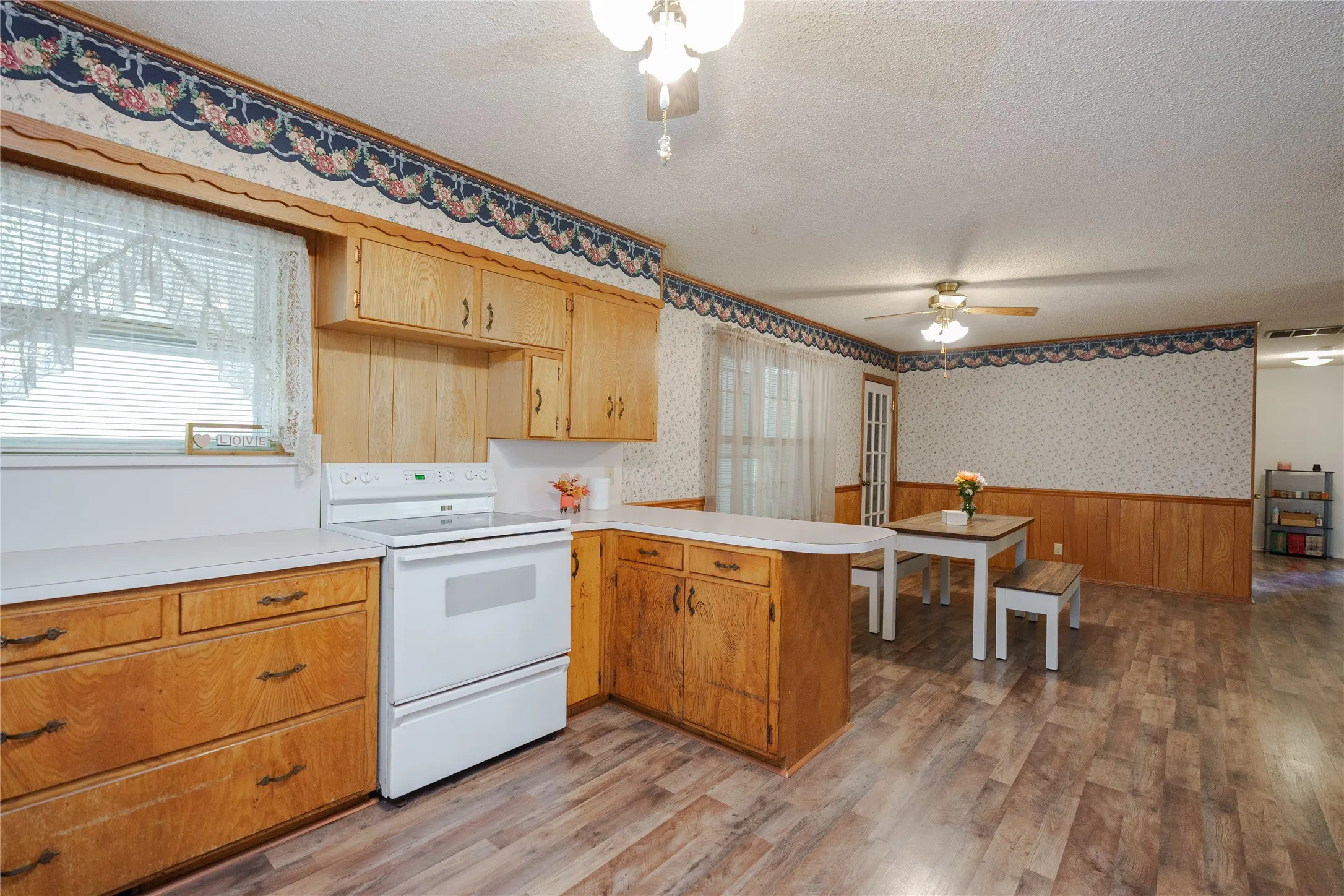 Kitchen featuring wood cabinetry, white countertops, built-in range, and wood-finish flooring