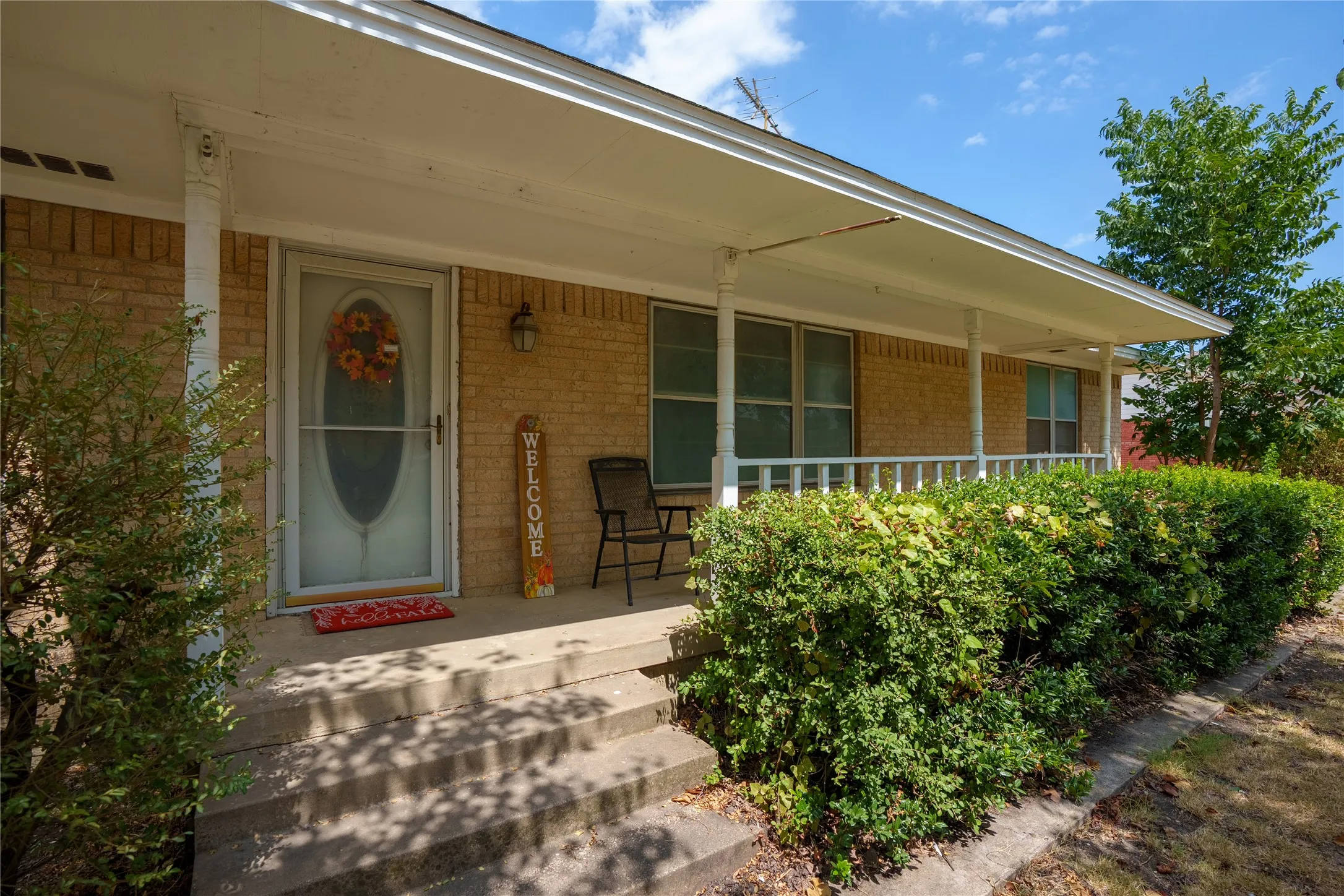 Brick facade with covered front porch, white columns, and a white porch railing
