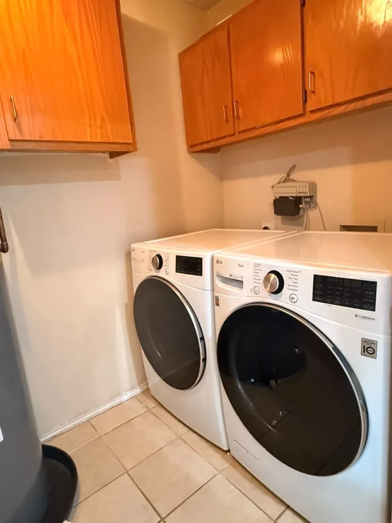 Built-in upper cabinetry with wood finish, light-toned wall paint, and tiled flooring