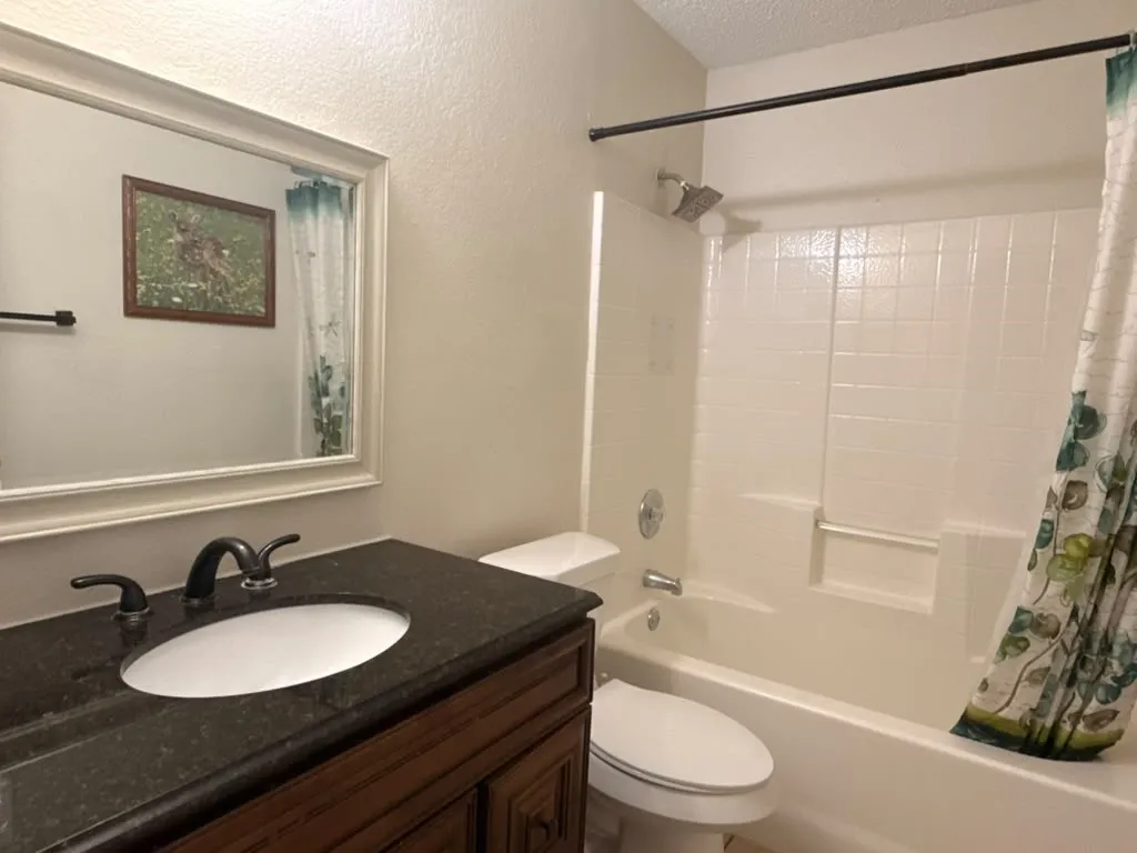 Dark countertop vanity with an undermount sink, dark bronze-finish faucet, and a large framed mirror