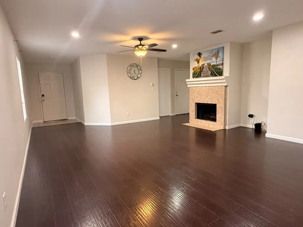 Wood-finish flooring throughout, recessed lighting, ceiling fan, and a fireplace with a stone surround