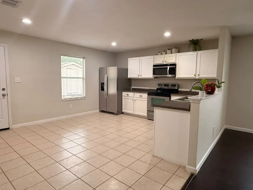 Kitchen featuring white cabinetry, stainless steel appliances, dark countertops, and recessed lighting