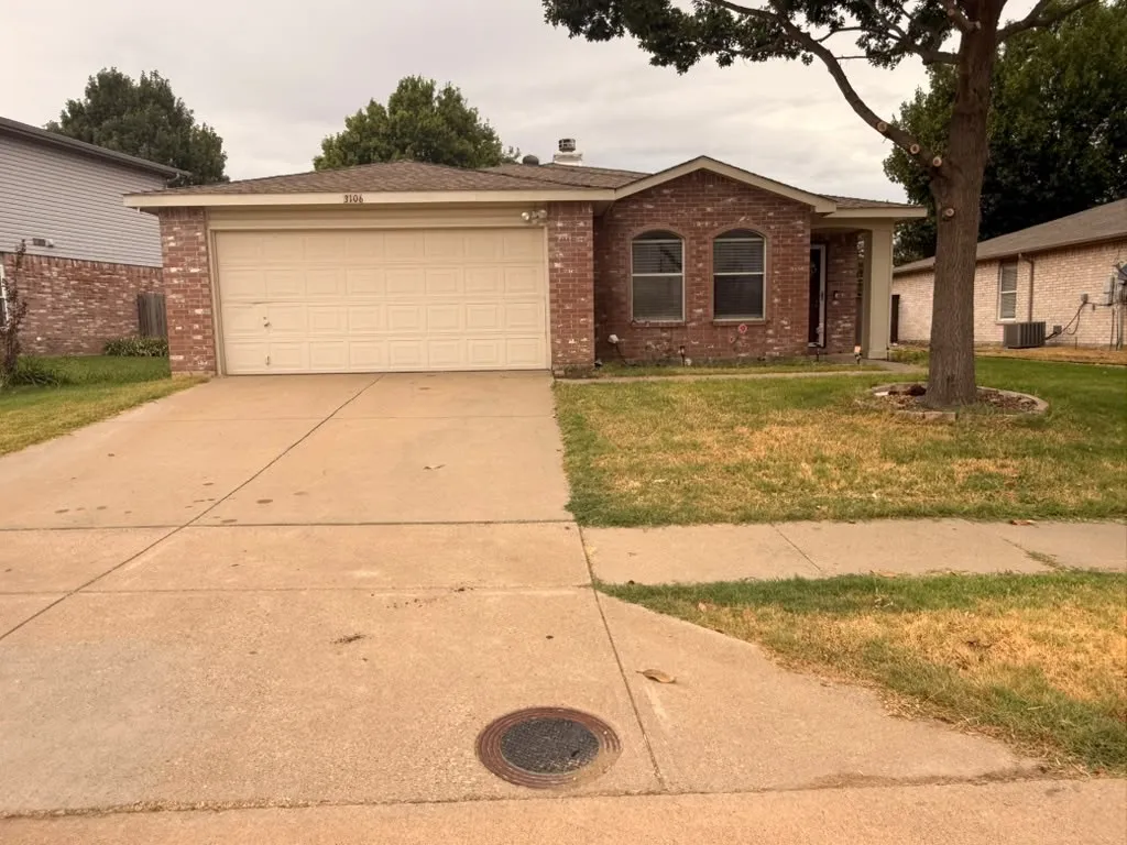Brick exterior with arched windows, an attached garage, and a concrete driveway