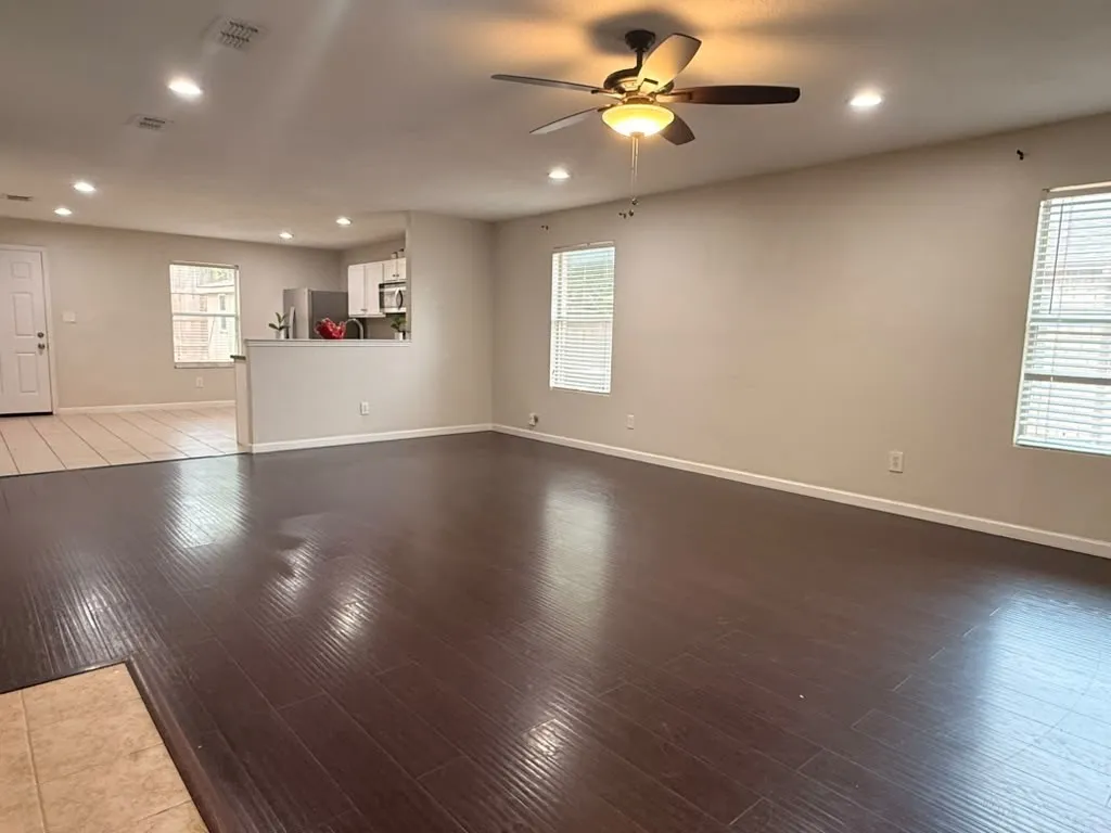 Spacious living area featuring wood-finish flooring, recessed lighting, and a ceiling fan