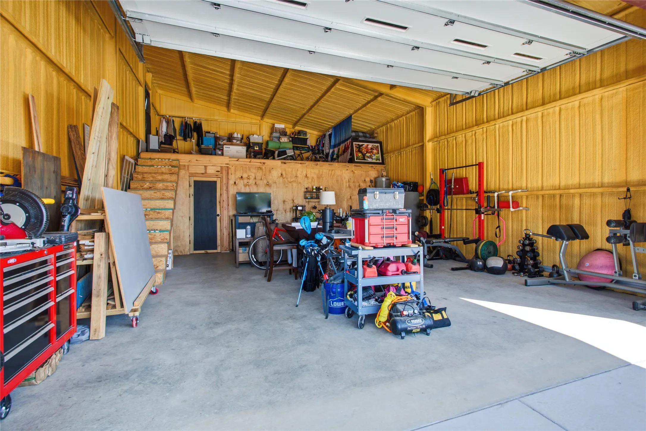 Large garage space with a concrete floor, corrugated metal walls, and an overhead garage door