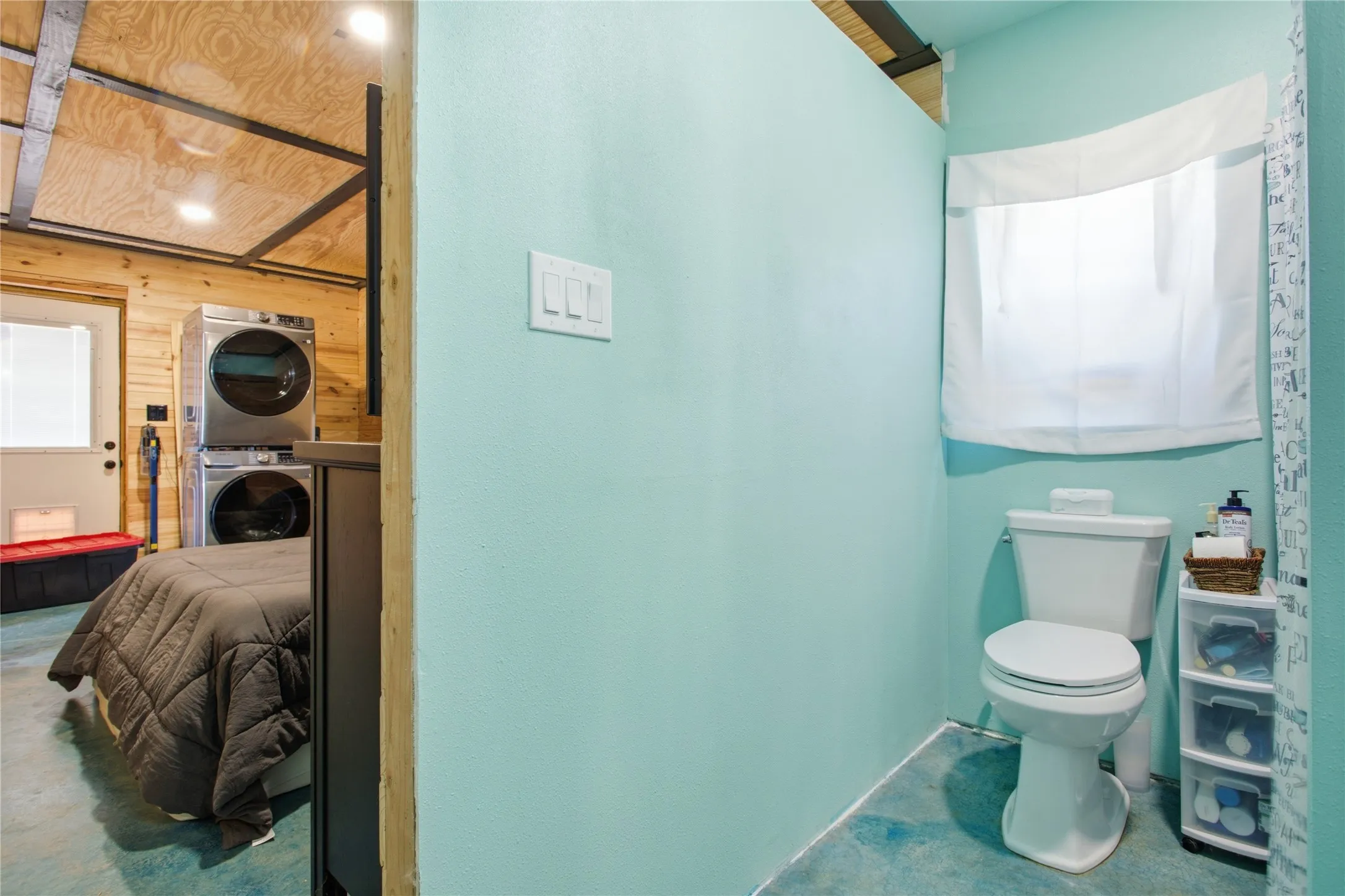 Compact bathroom suite featuring turquoise wall finishes, a standard toilet with tank, and a curved shower enclosure with frosted glass panel