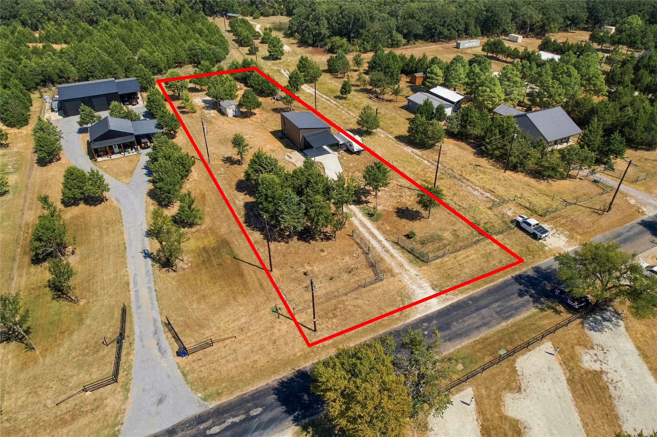 Expansive property featuring multiple structures, gravel driveways, perimeter fencing, and mature trees