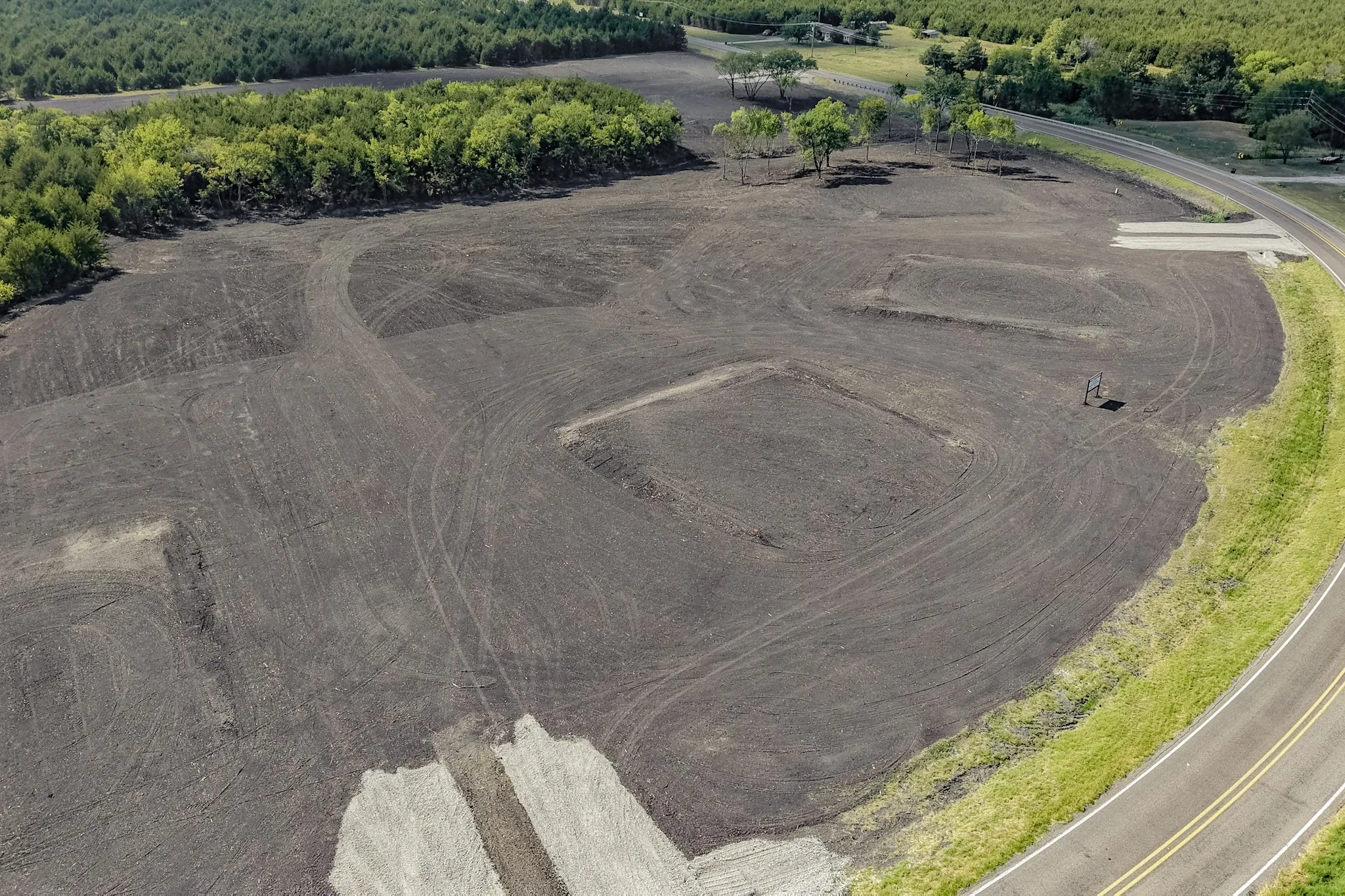 Expansive cleared lot with perimeter tree lines and partial road frontage