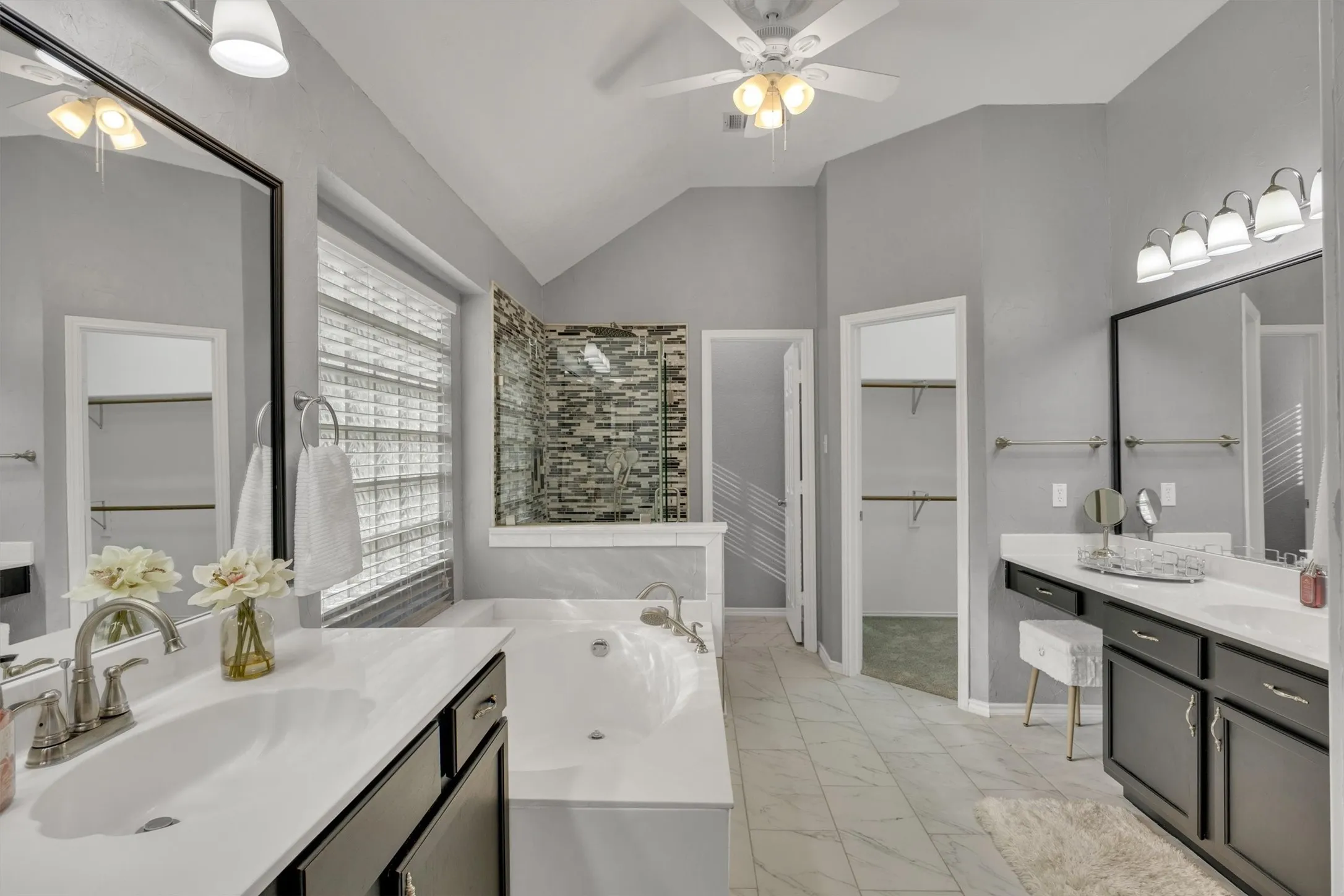 Fully renovated primary bathroom with walk-in custom closet, two separate vanities, soaker tub and walk in shower