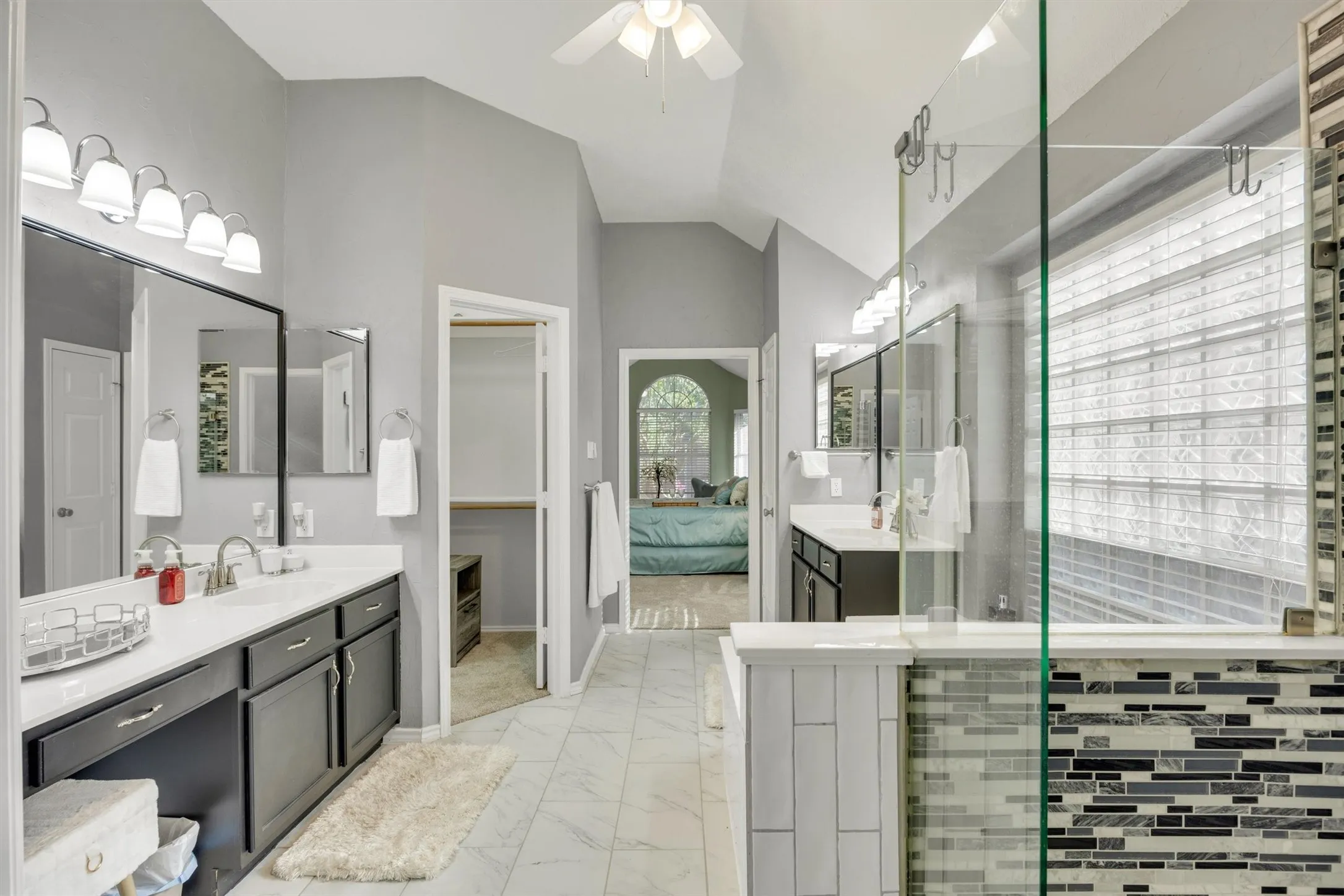 Fully renovated primary bathroom with walk-in custom closet, two separate vanities, soaker tub and walk in shower
