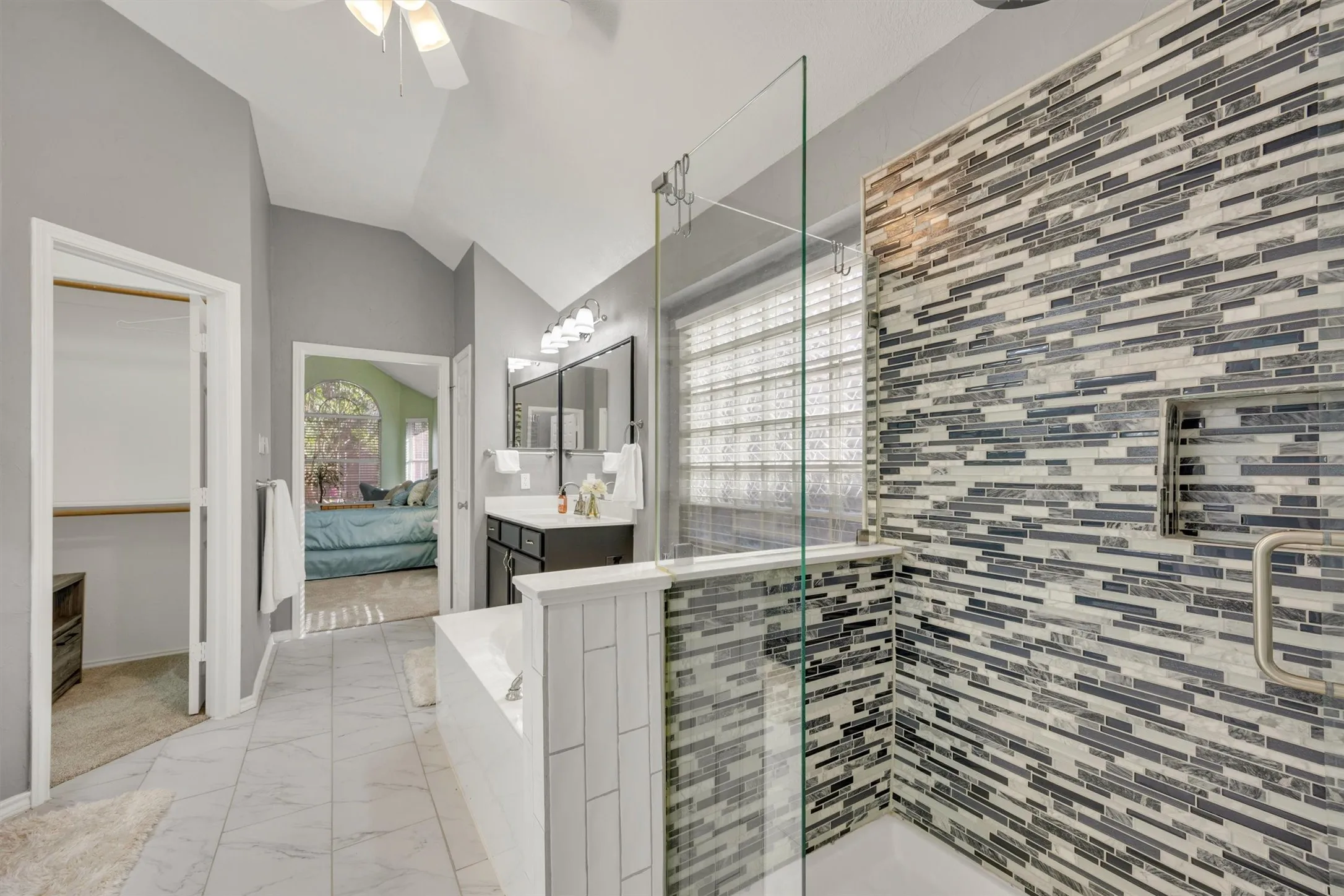 Fully renovated primary bathroom with walk-in custom closet, two separate vanities, soaker tub and walk in shower
