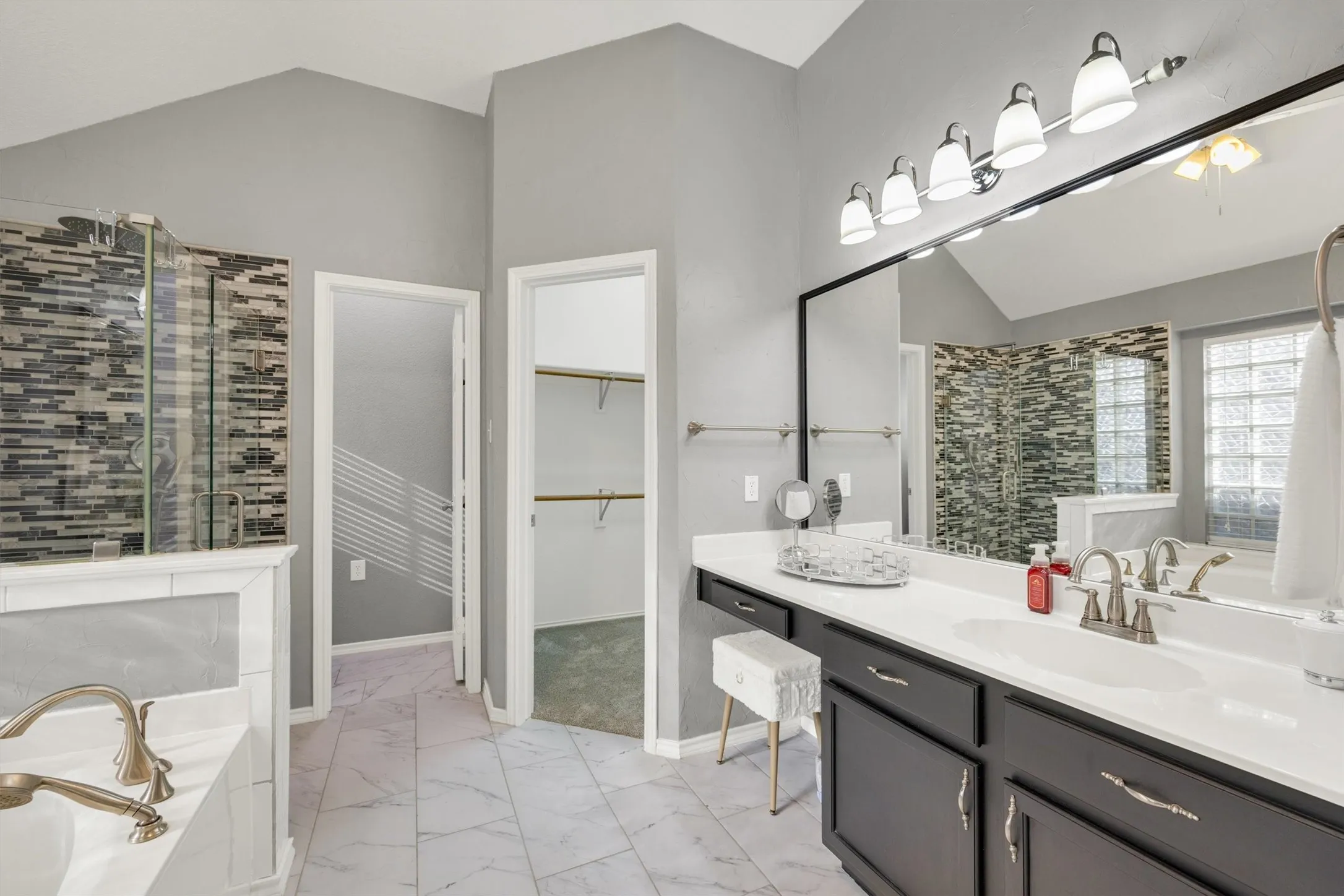 Fully renovated primary bathroom with walk-in custom closet, two separate vanities, soaker tub and walk in shower