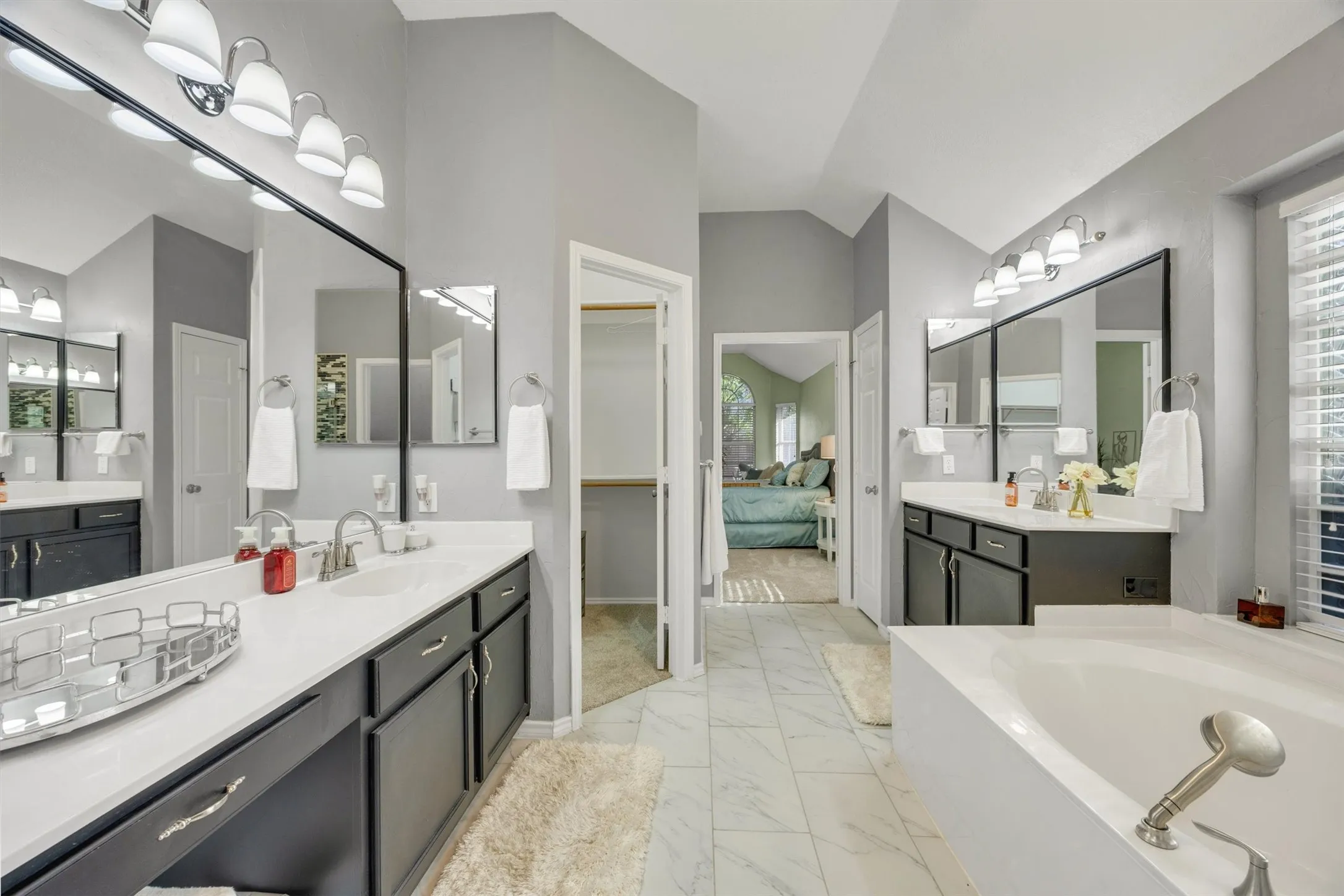 Fully renovated primary bathroom with walk-in custom closet, two separate vanities, soaker tub and walk in shower