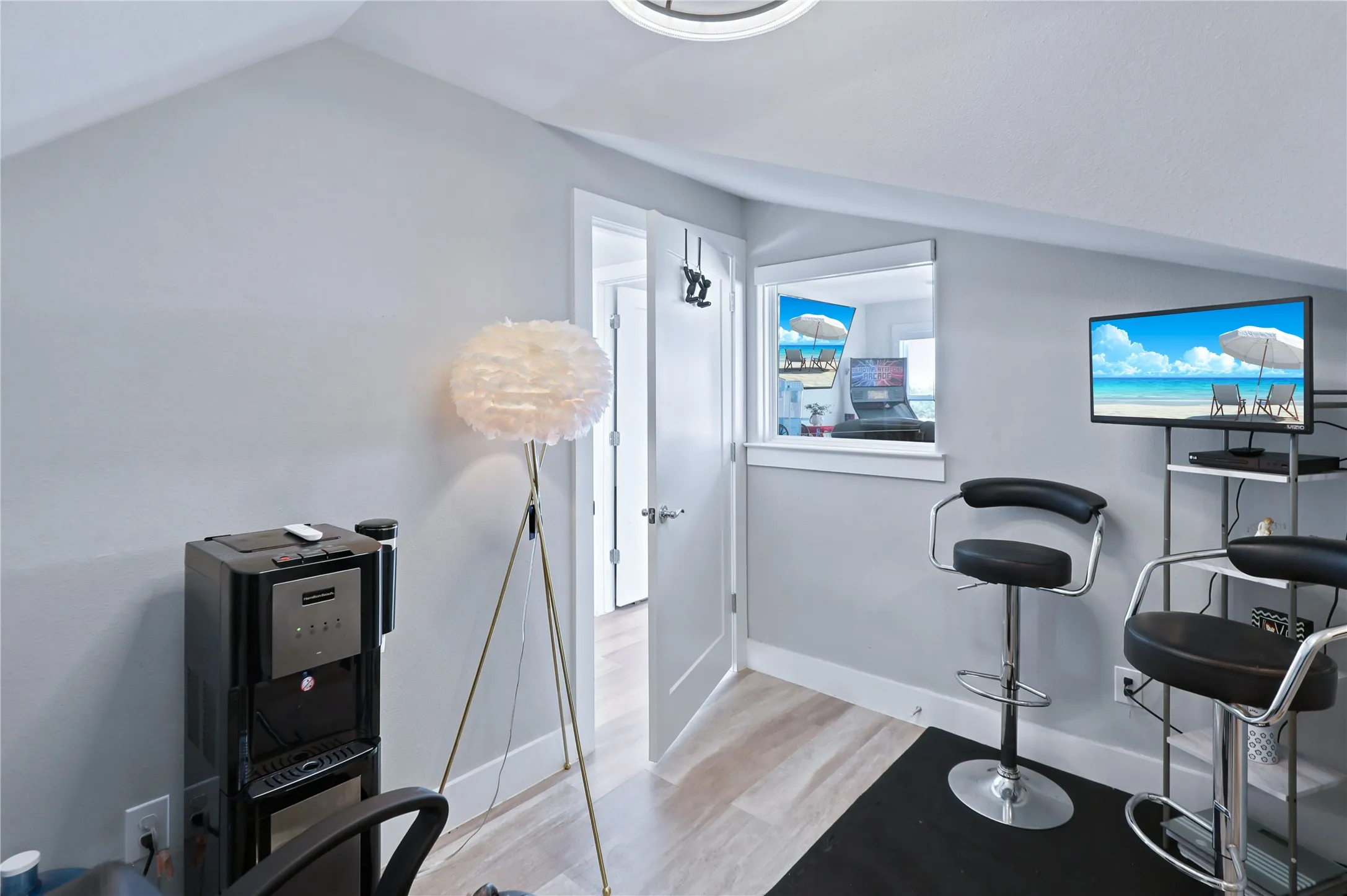 Angled ceiling with recessed lighting, light wood-finish flooring, white trim, and a white interior door