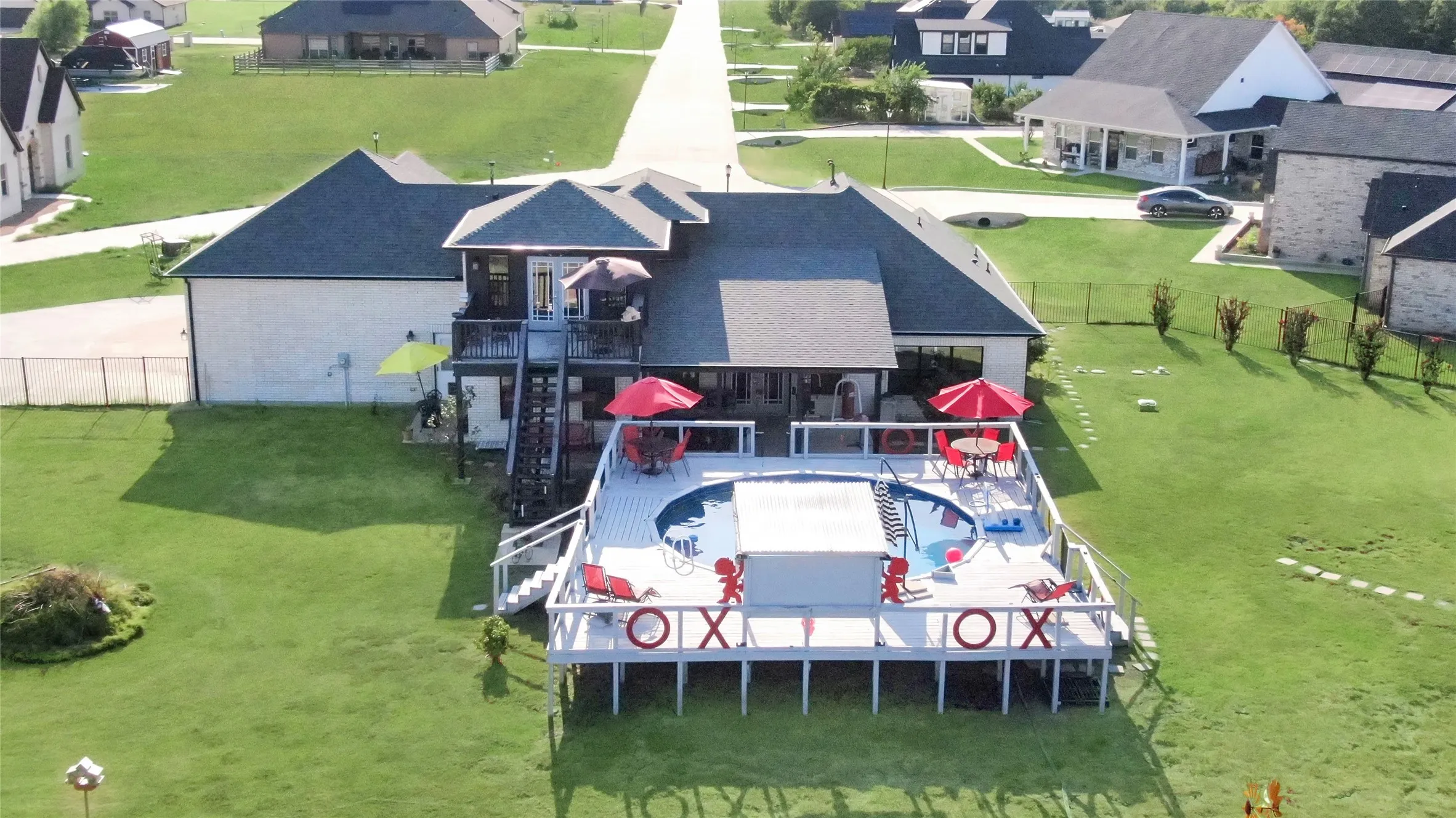 Expansive elevated deck with an integrated circular pool, extending from a two-story residence with multiple outdoor living areas