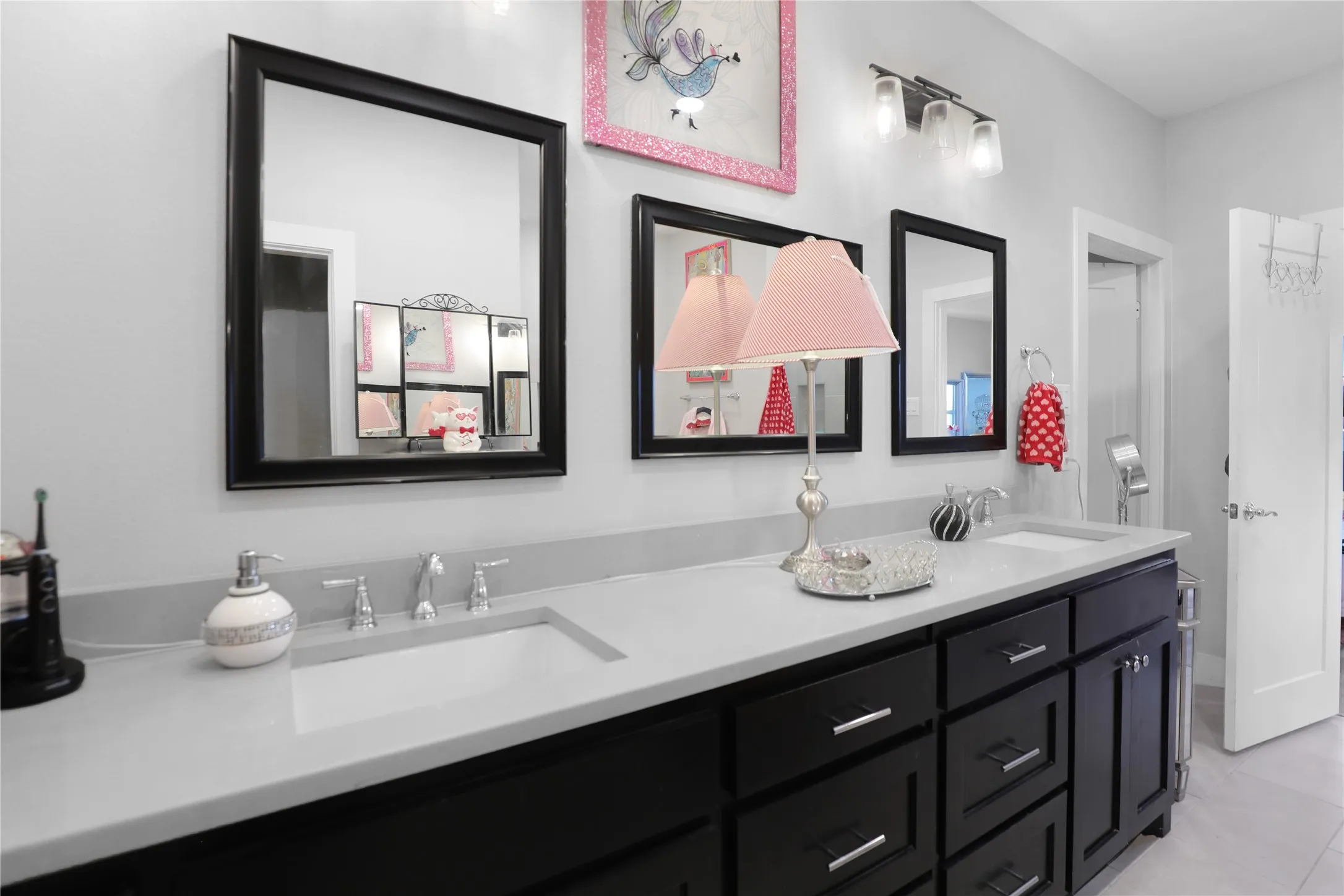 Dual vanity with dark wood-finish cabinetry, integrated sinks, and polished chrome hardware