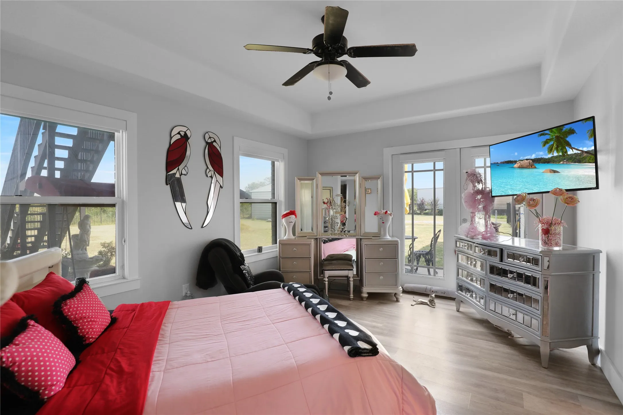 Tray ceiling with a ceiling fan, dual windows, and French doors providing exterior access
