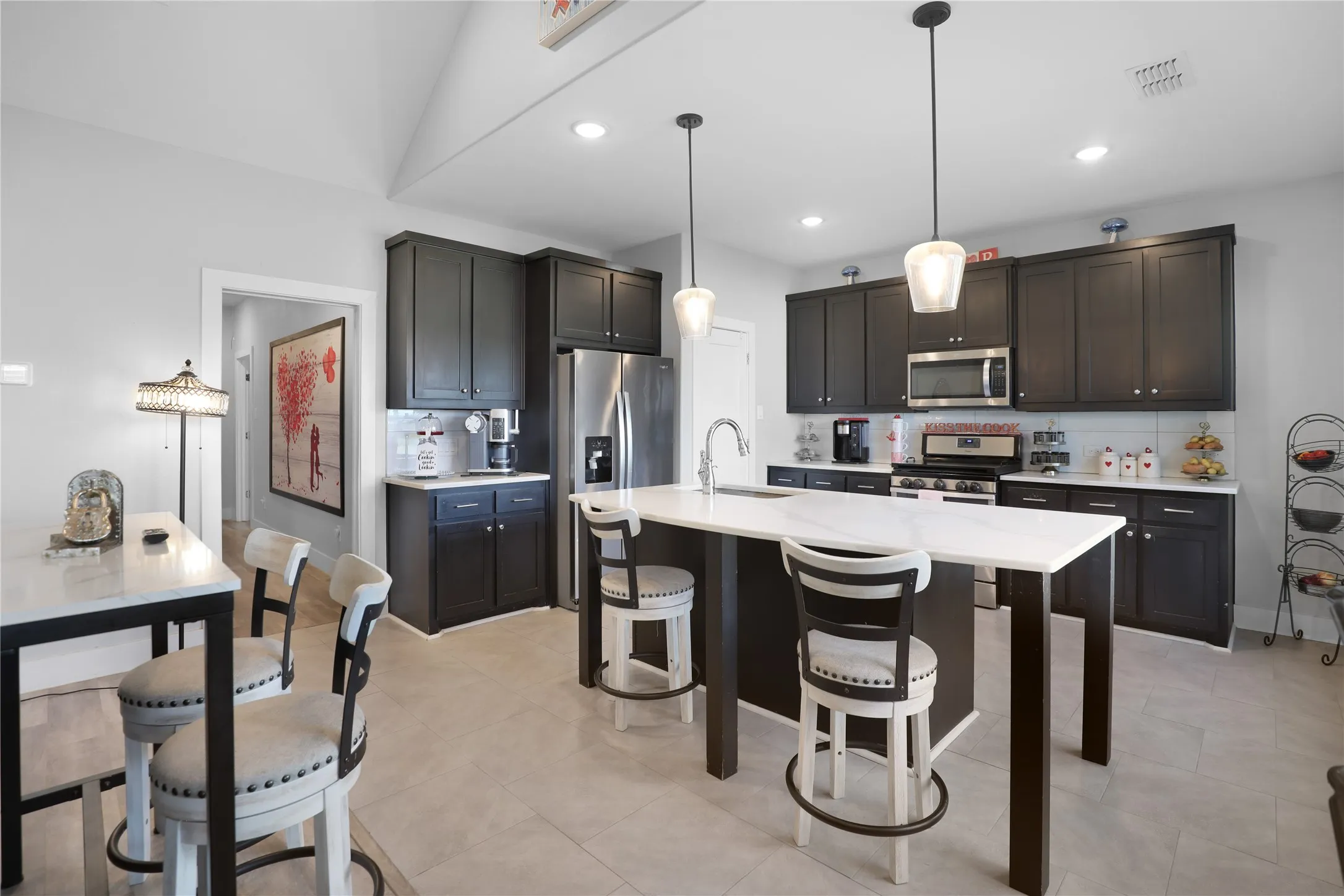 Kitchen featuring dark wood-finish cabinetry, stainless steel appliances, a white tile backsplash, and a central island with a white countertop