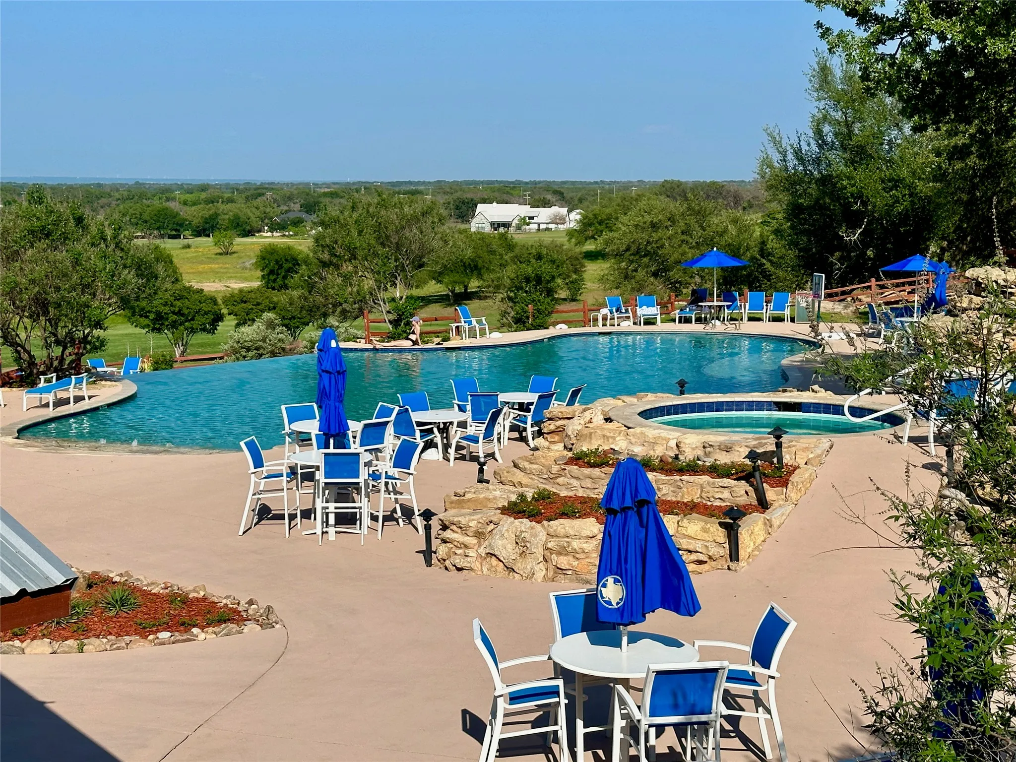 Expansive outdoor living area featuring a large swimming pool, an attached spa, and a concrete patio
