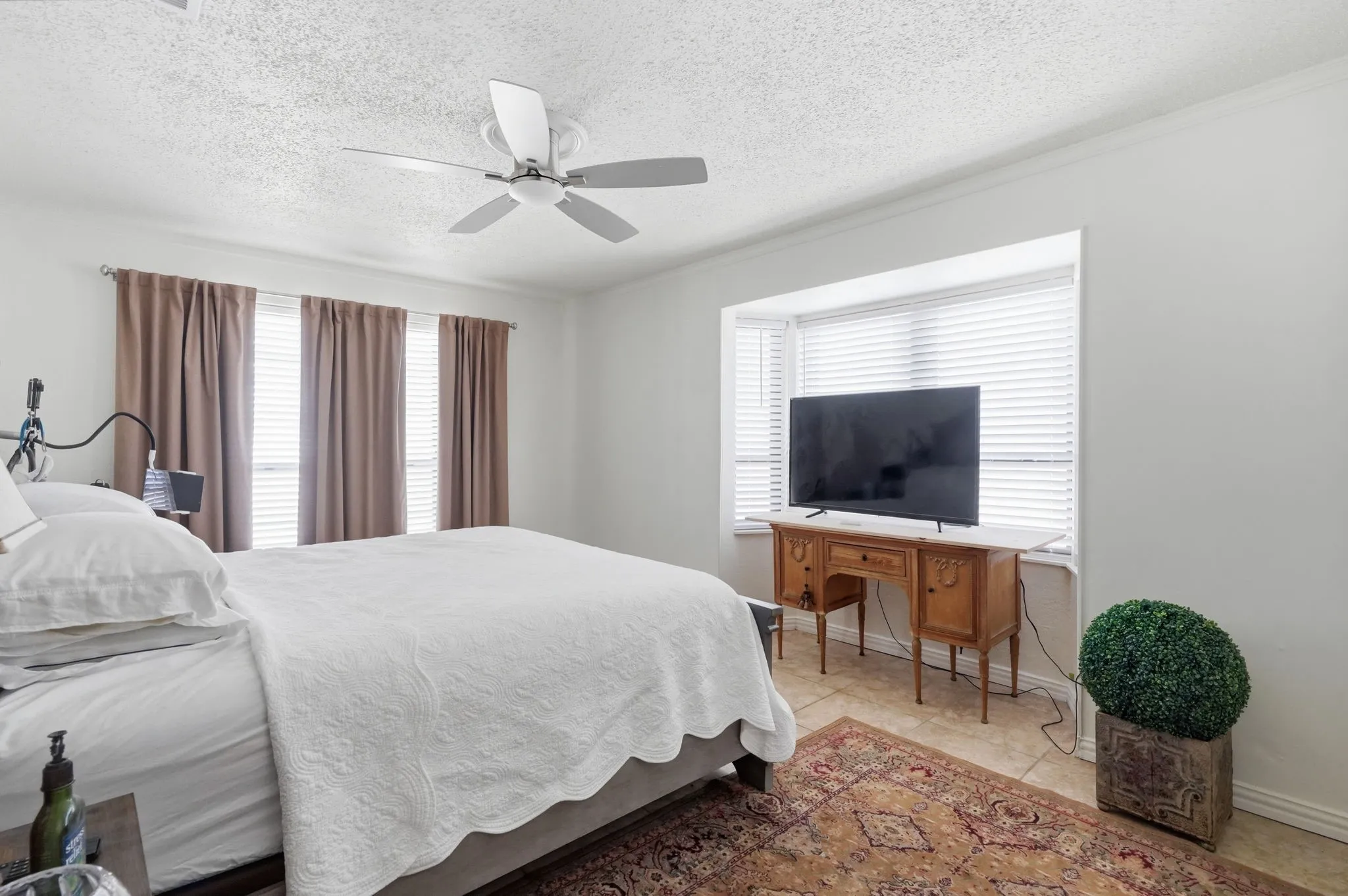 Recessed bay window, ceiling fan, crown molding, white walls, and tile flooring