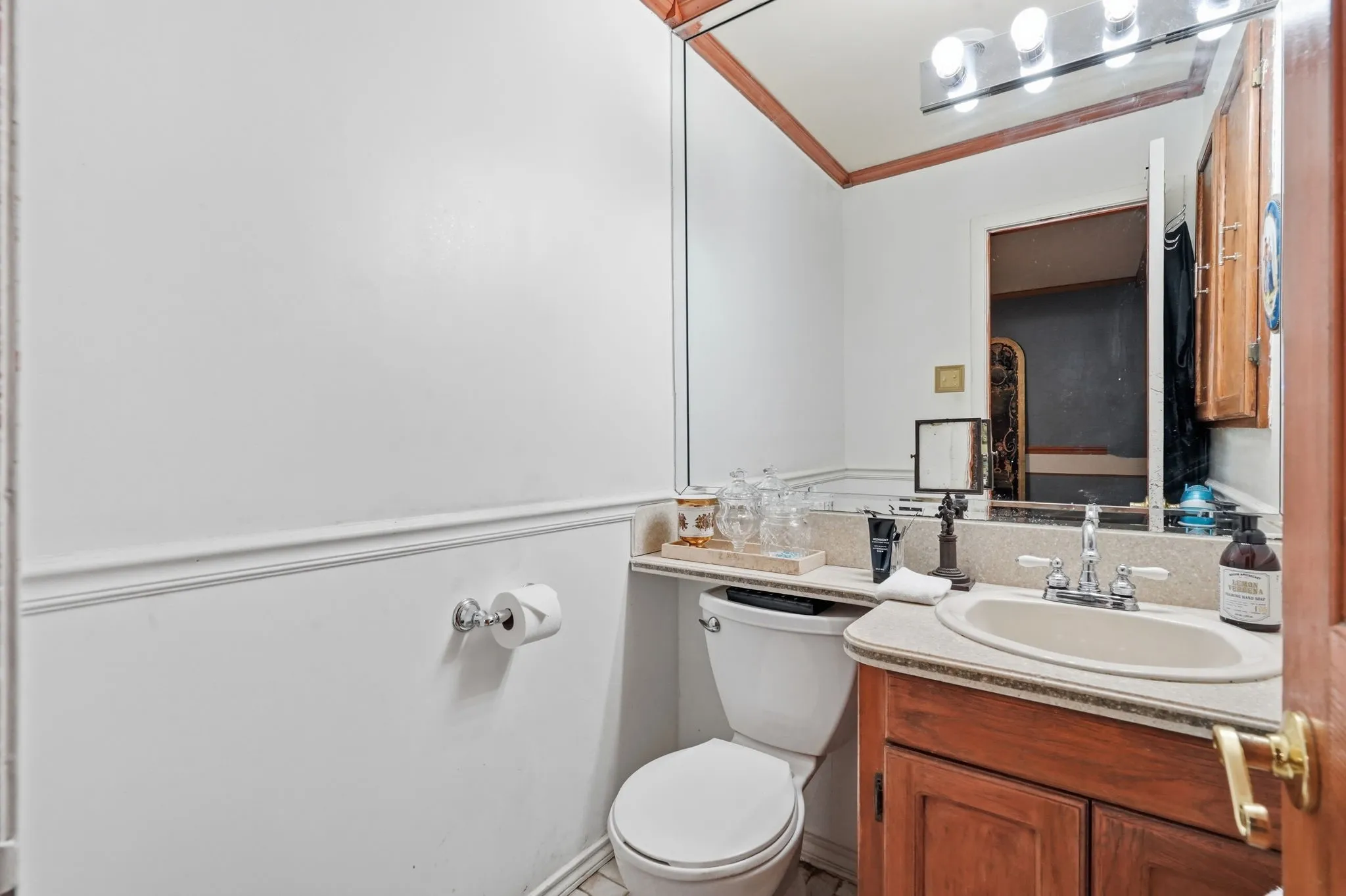 Bathroom featuring a vanity with wood-finish cabinetry, an integrated sink, and a large wall mirror