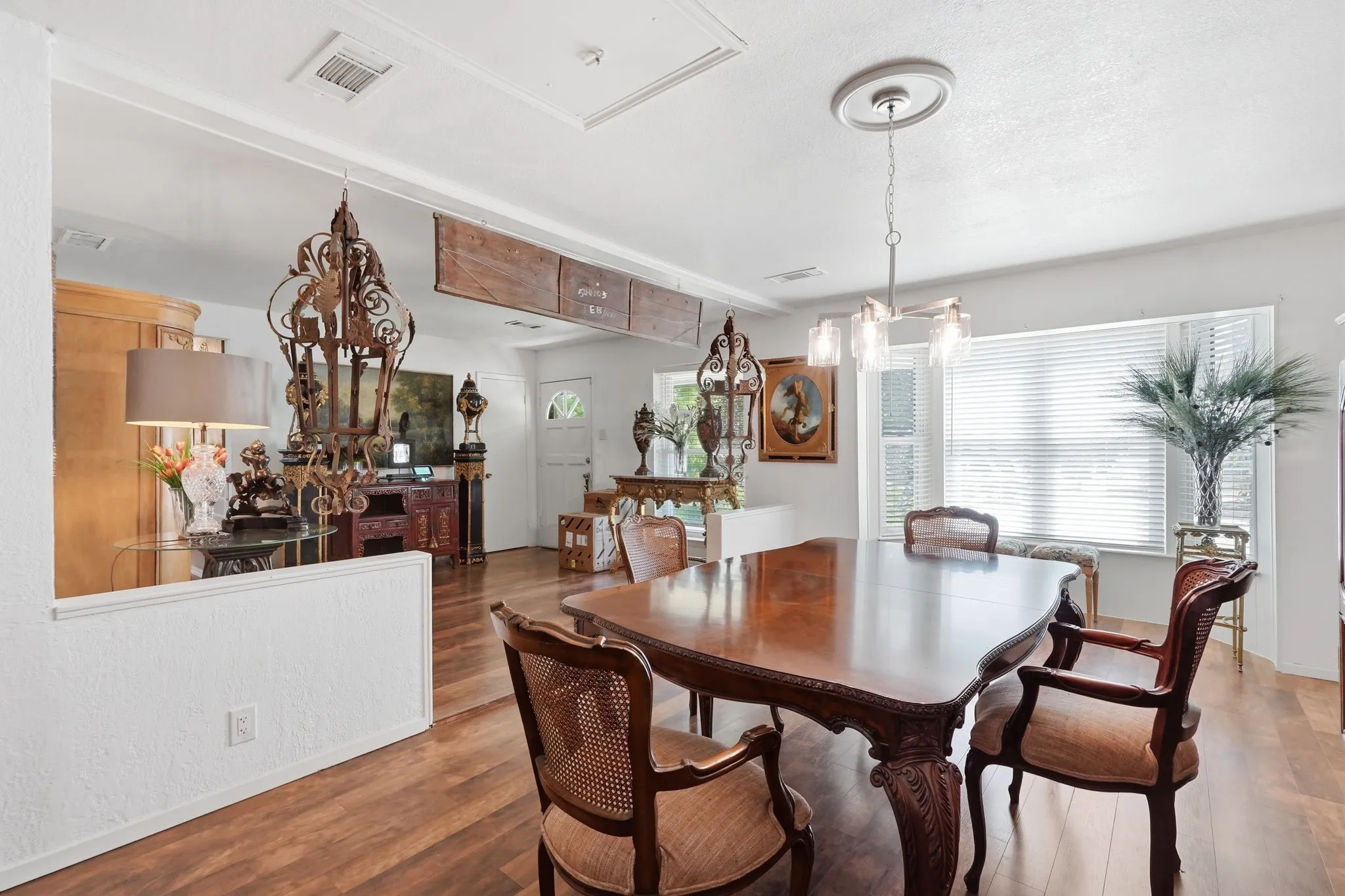 Dining area featuring a contemporary chandelier, wood-finish flooring, and a large window with blinds
