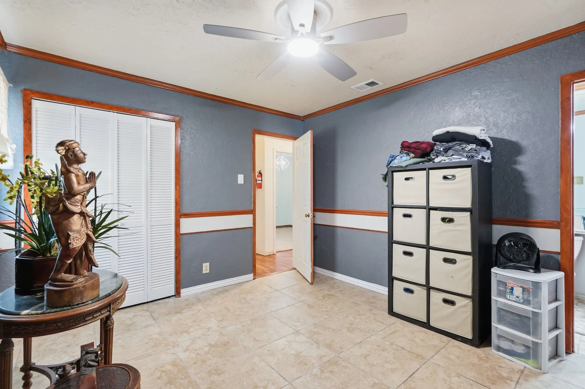 Tile flooring, two-tone wall treatment, wood trim accents, bifold closet doors, and a ceiling fan with integrated lighting