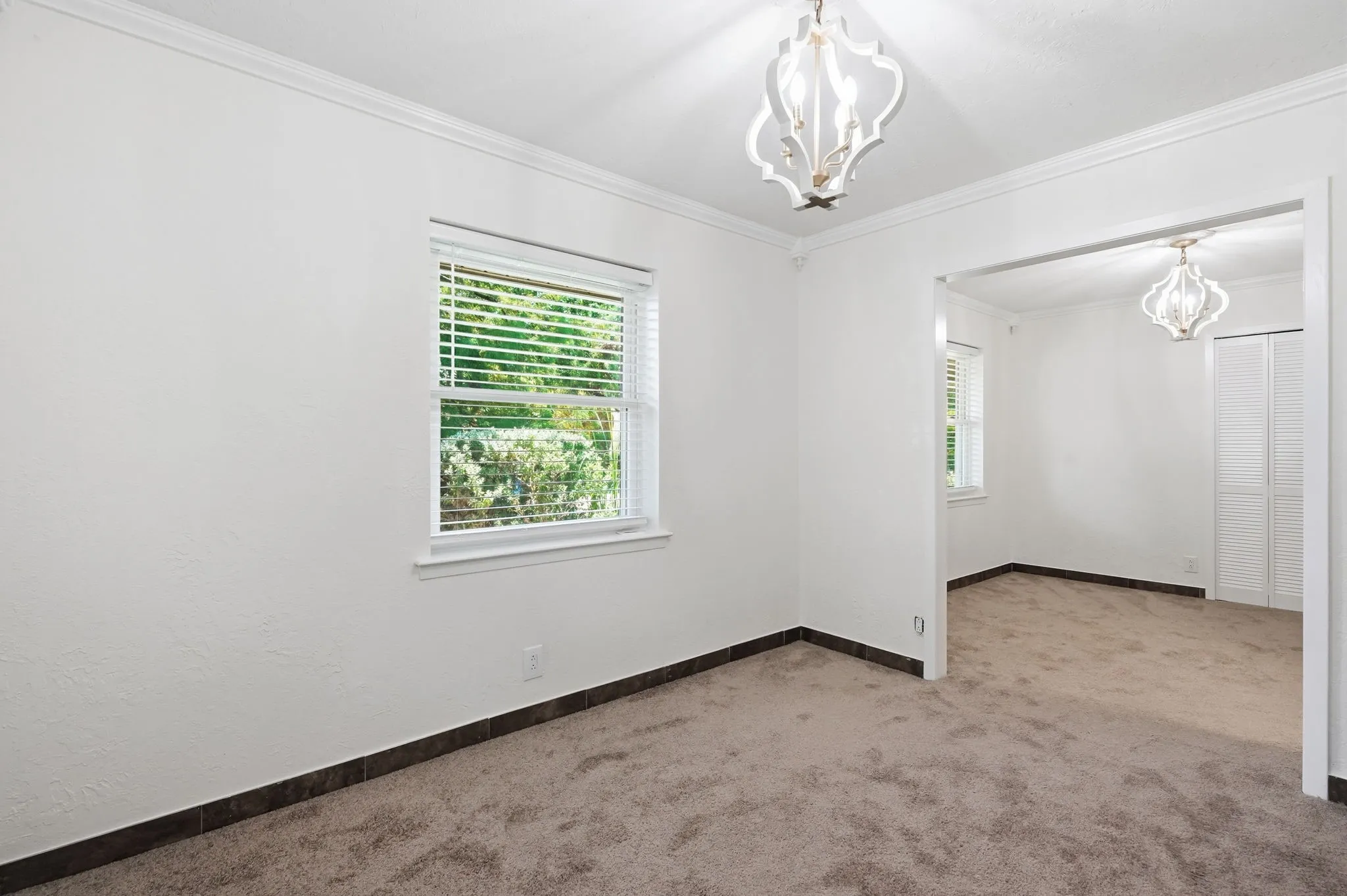 Recessed window with horizontal blinds, decorative ceiling light fixtures, and crown molding