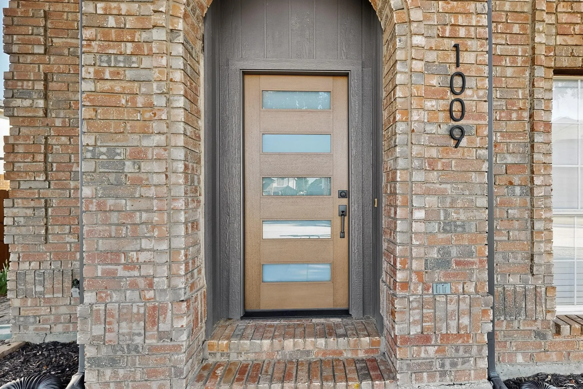Brick exterior entry featuring an arched doorway