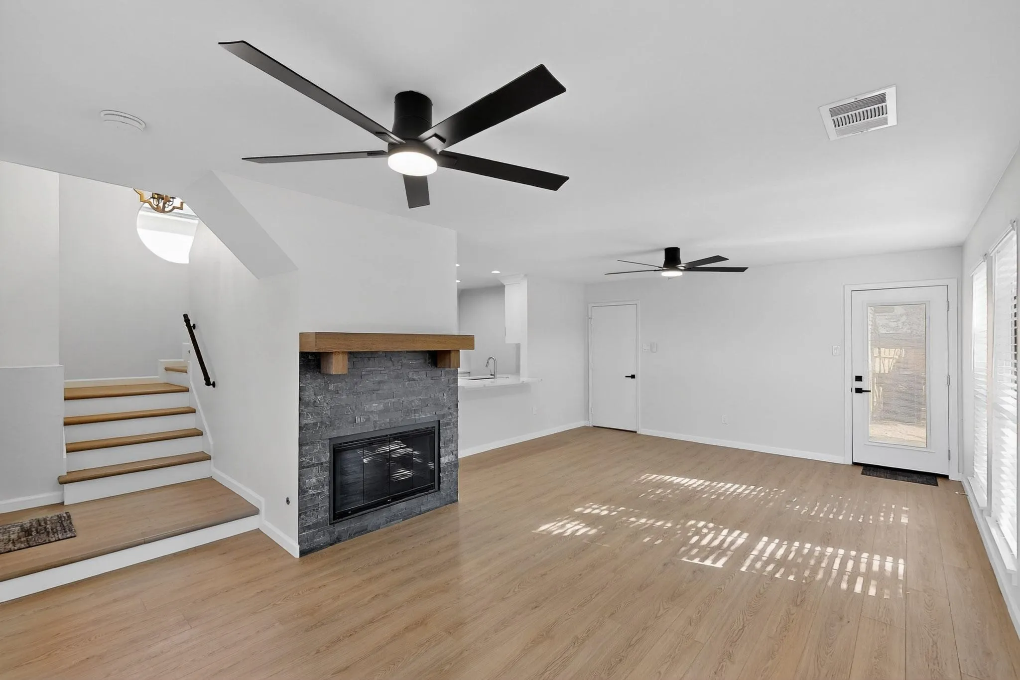 Wood-finish flooring throughout, with a stone-clad fireplace featuring a wood mantel