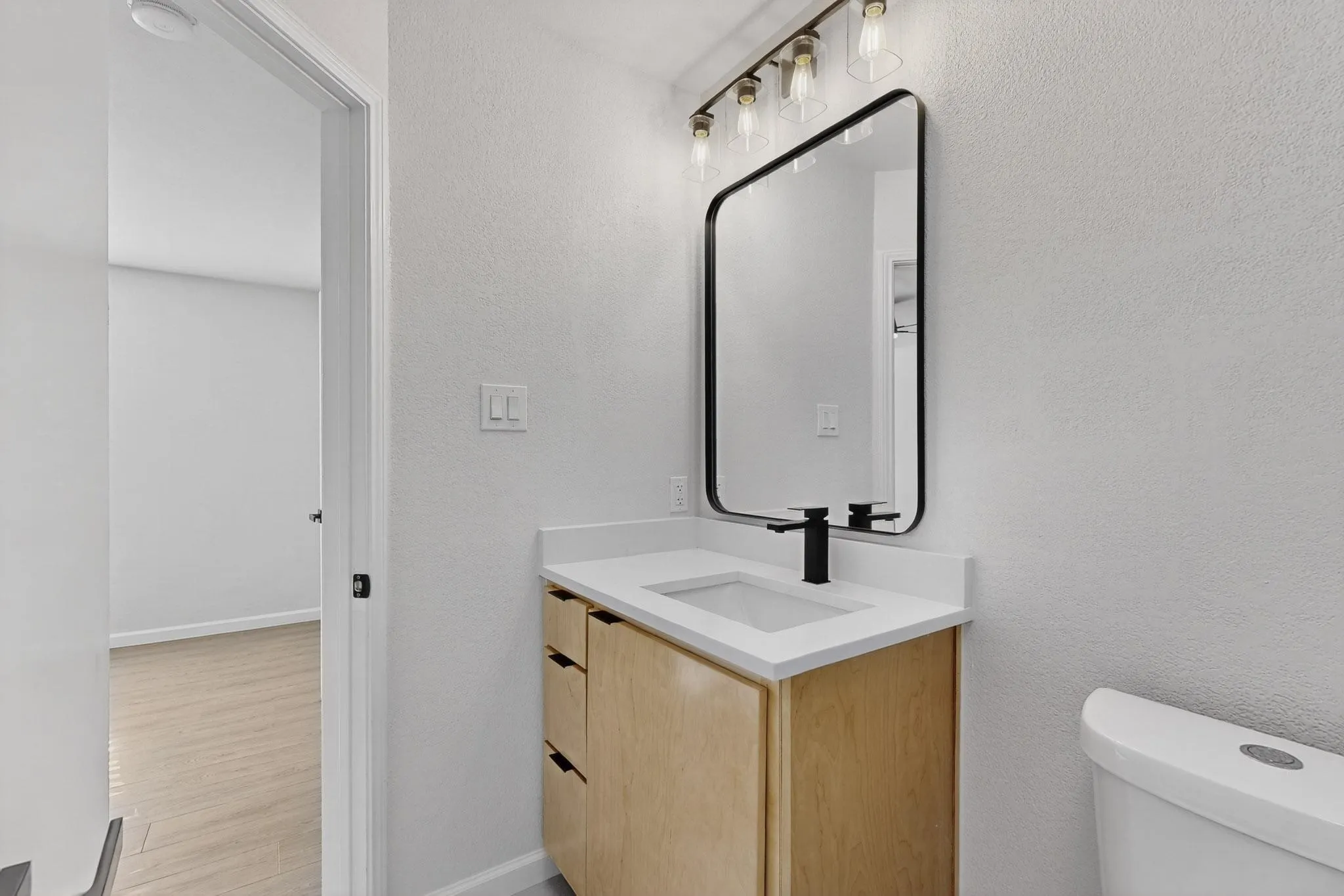 Modern vanity with light wood-finish cabinetry and black hardware