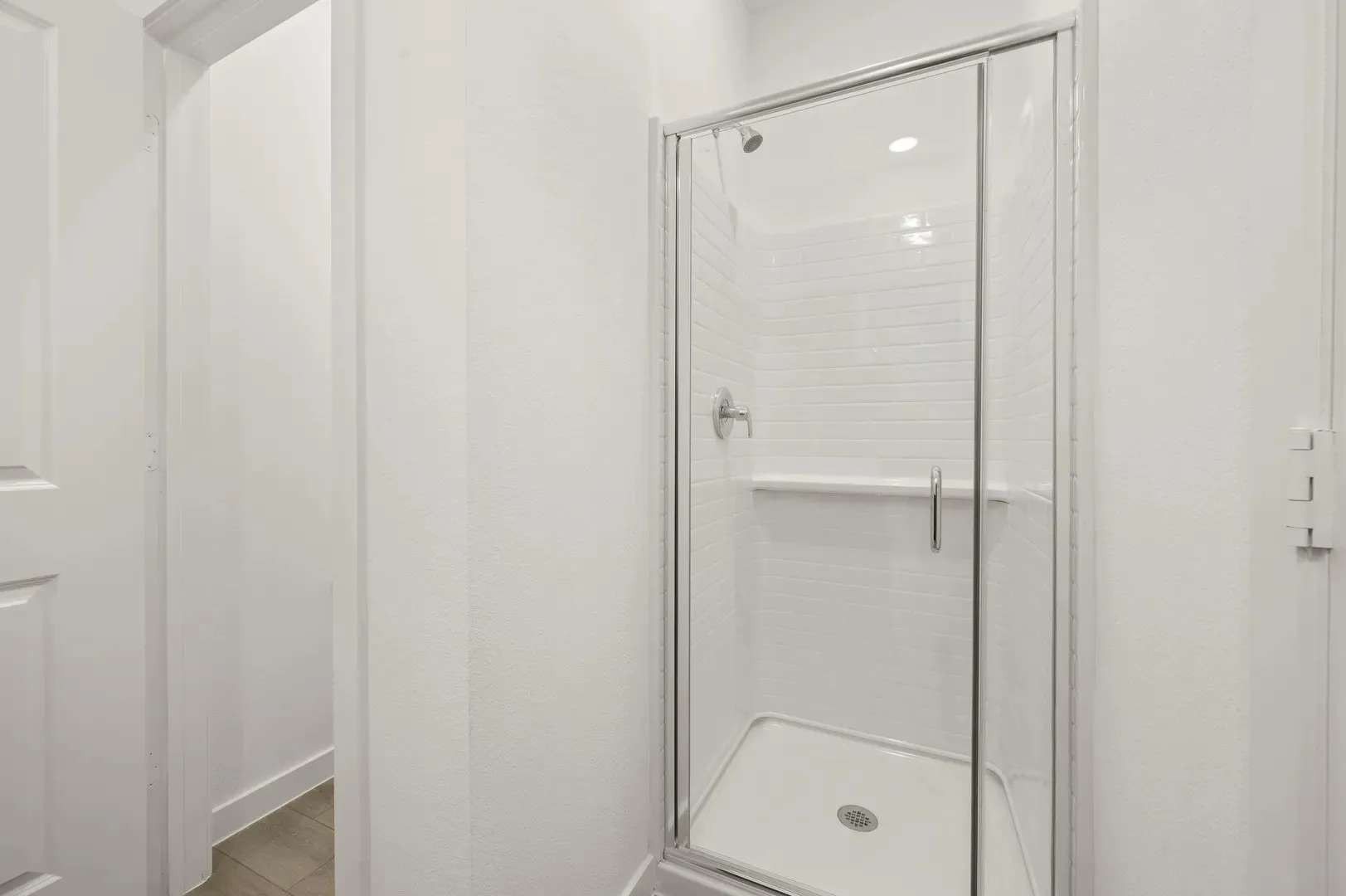 Frameless glass shower enclosure featuring white subway tile, a built-in shower niche, and a chrome shower fixture