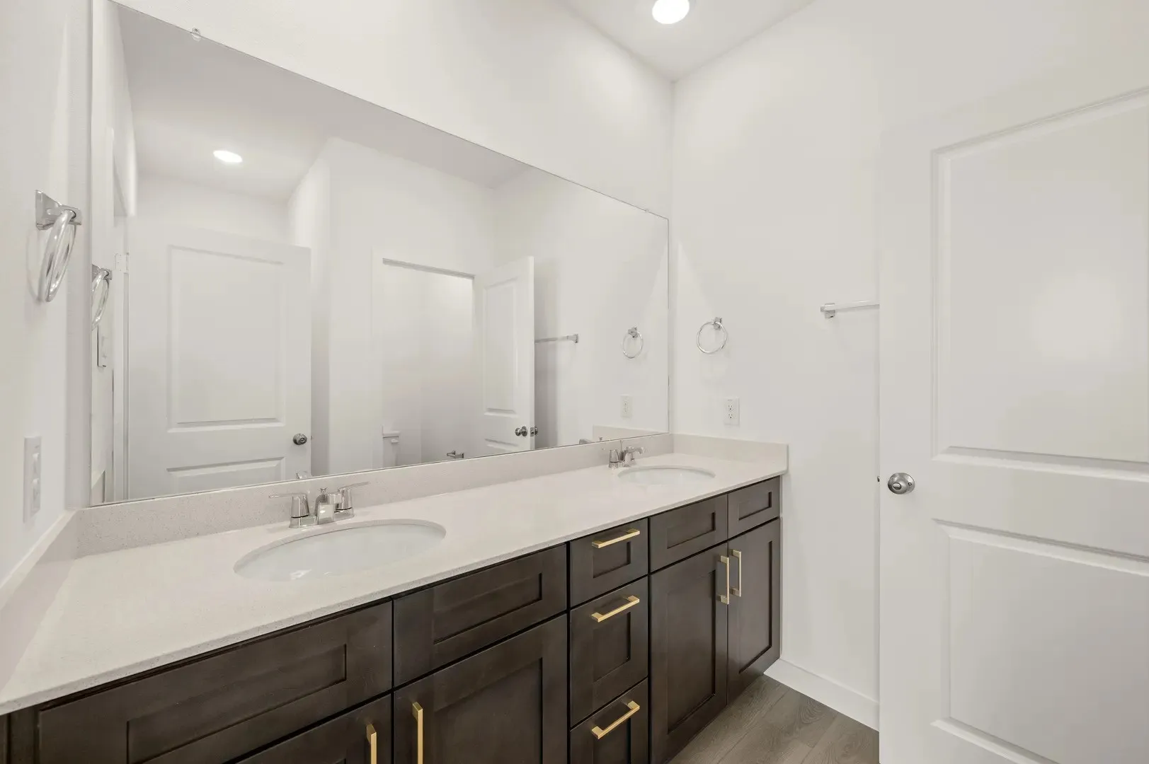 Double vanity with dark wood-finish cabinetry, light-toned countertops, and dual undermount sinks
