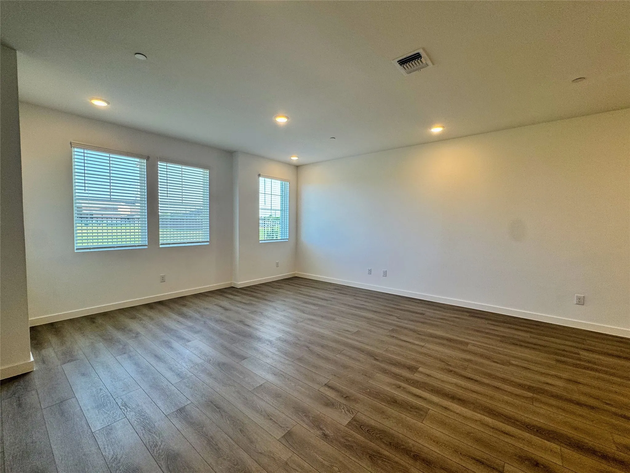 Spacious interior featuring wood-finish flooring, white baseboards, and recessed lighting