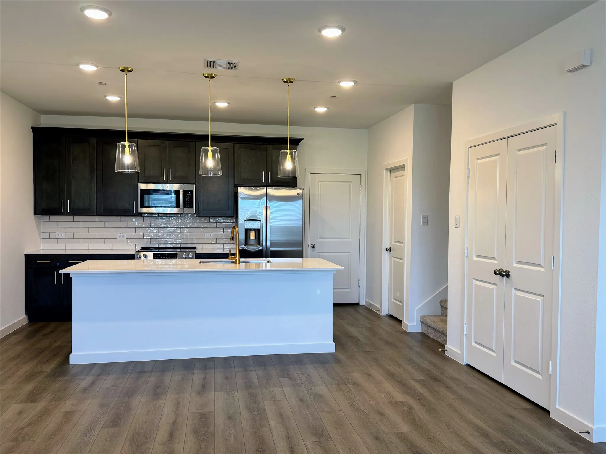 Modern kitchen featuring dark cabinetry, stainless steel appliances, and a subway tile backsplash