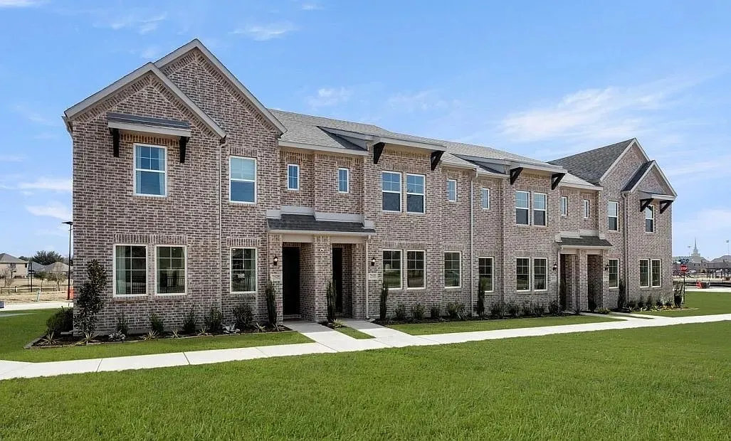 Modern townhome architecture featuring light gray brick, multiple gables, and dark accent awnings