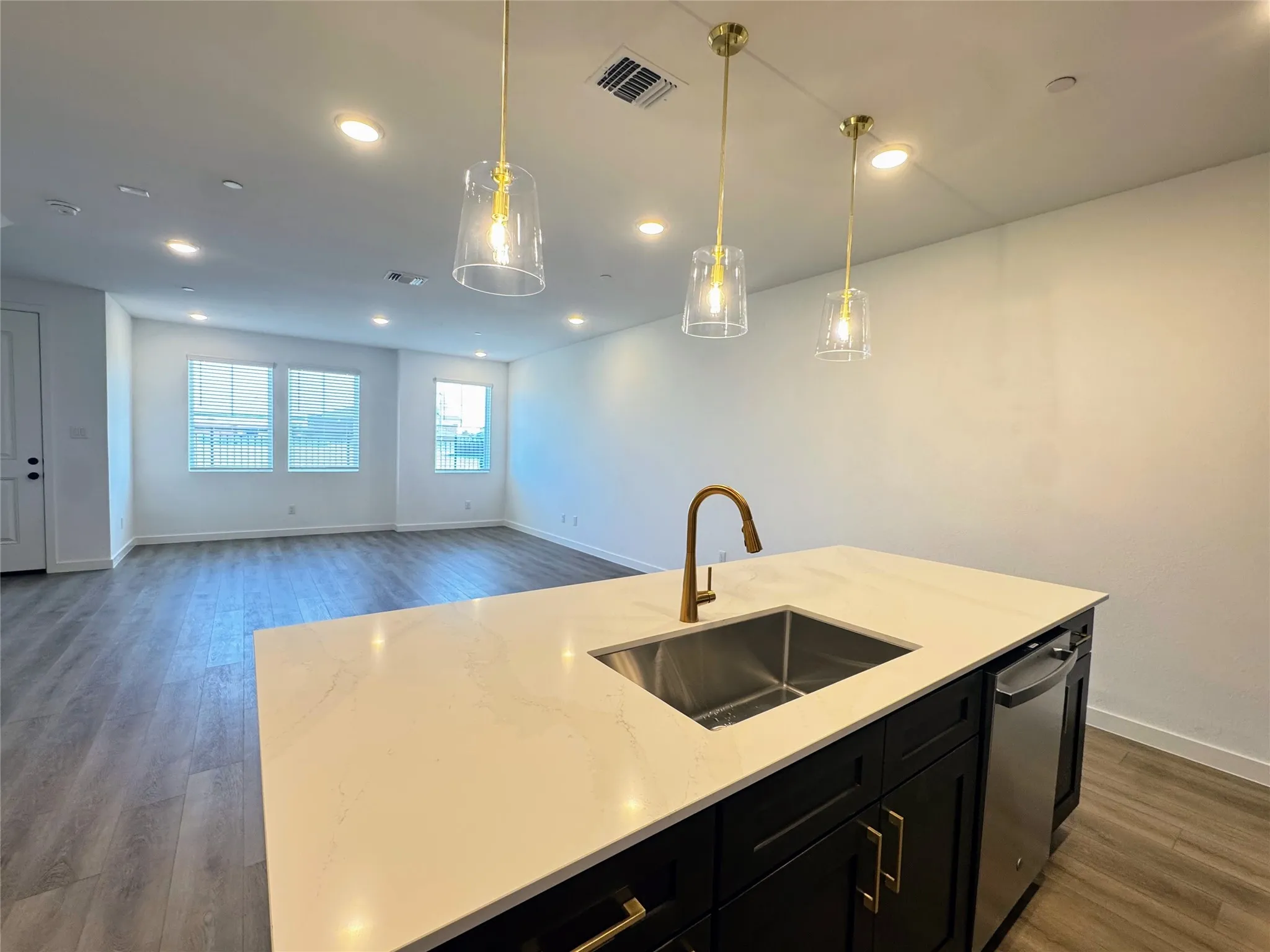 Kitchen island with a stainless steel sink, gold-tone faucet, and quartz countertop