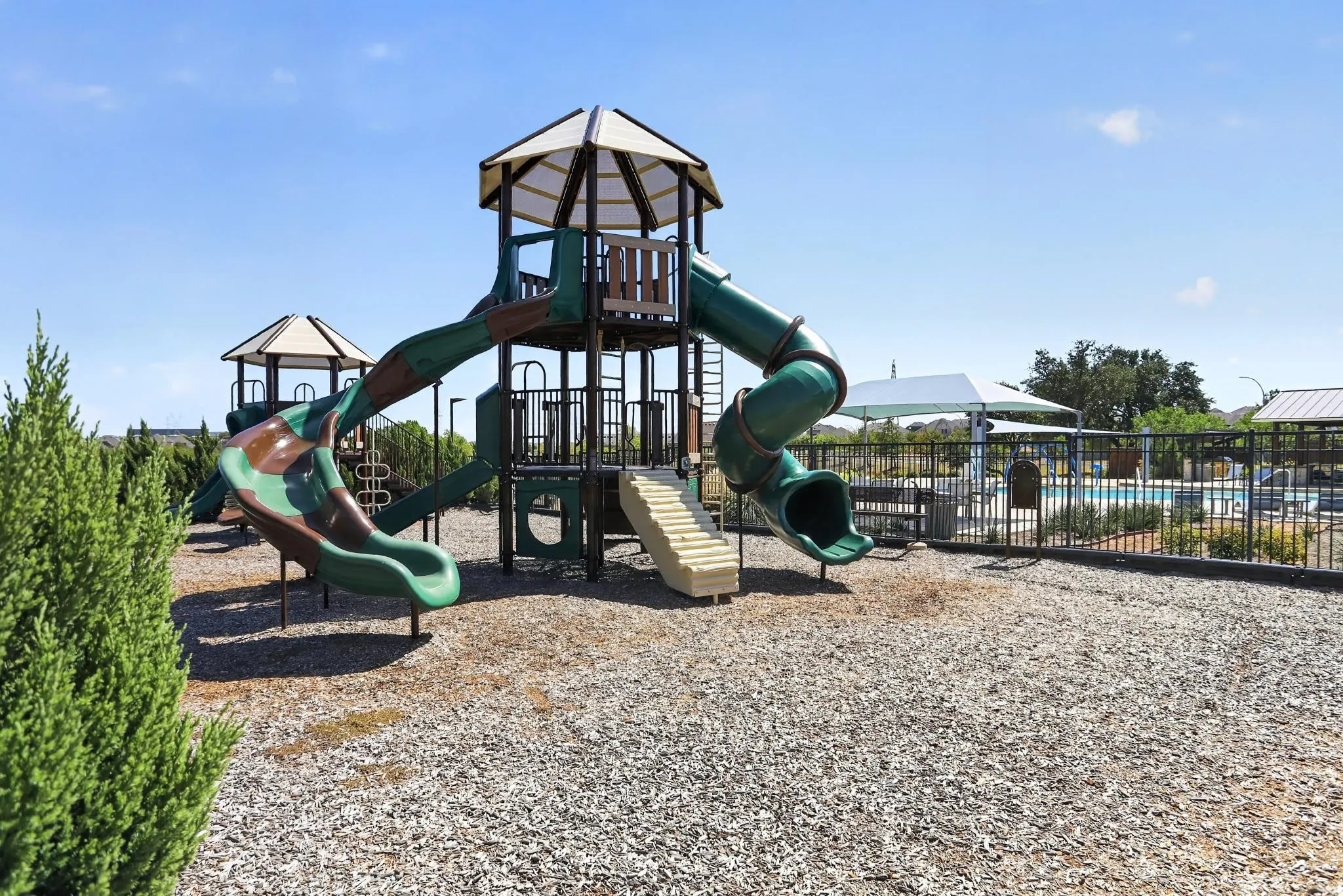 Playground structure with multiple slides, climbing elements, and protective ground cover