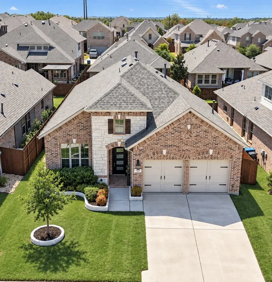 Brick and stone exterior with a two-car garage, concrete driveway, and a well-maintained lawn