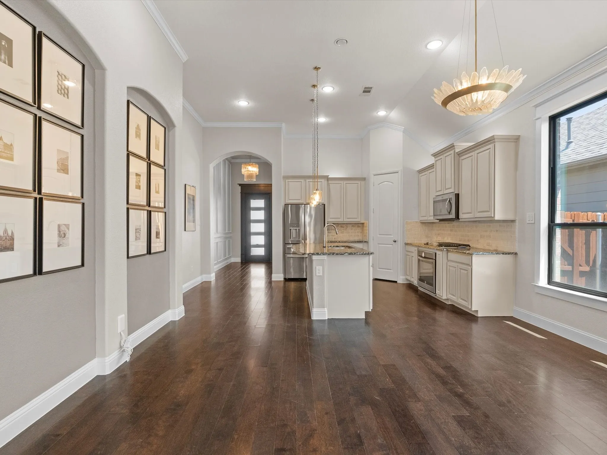 Open-concept living space with dark wood-finish flooring, recessed lighting, and crown molding