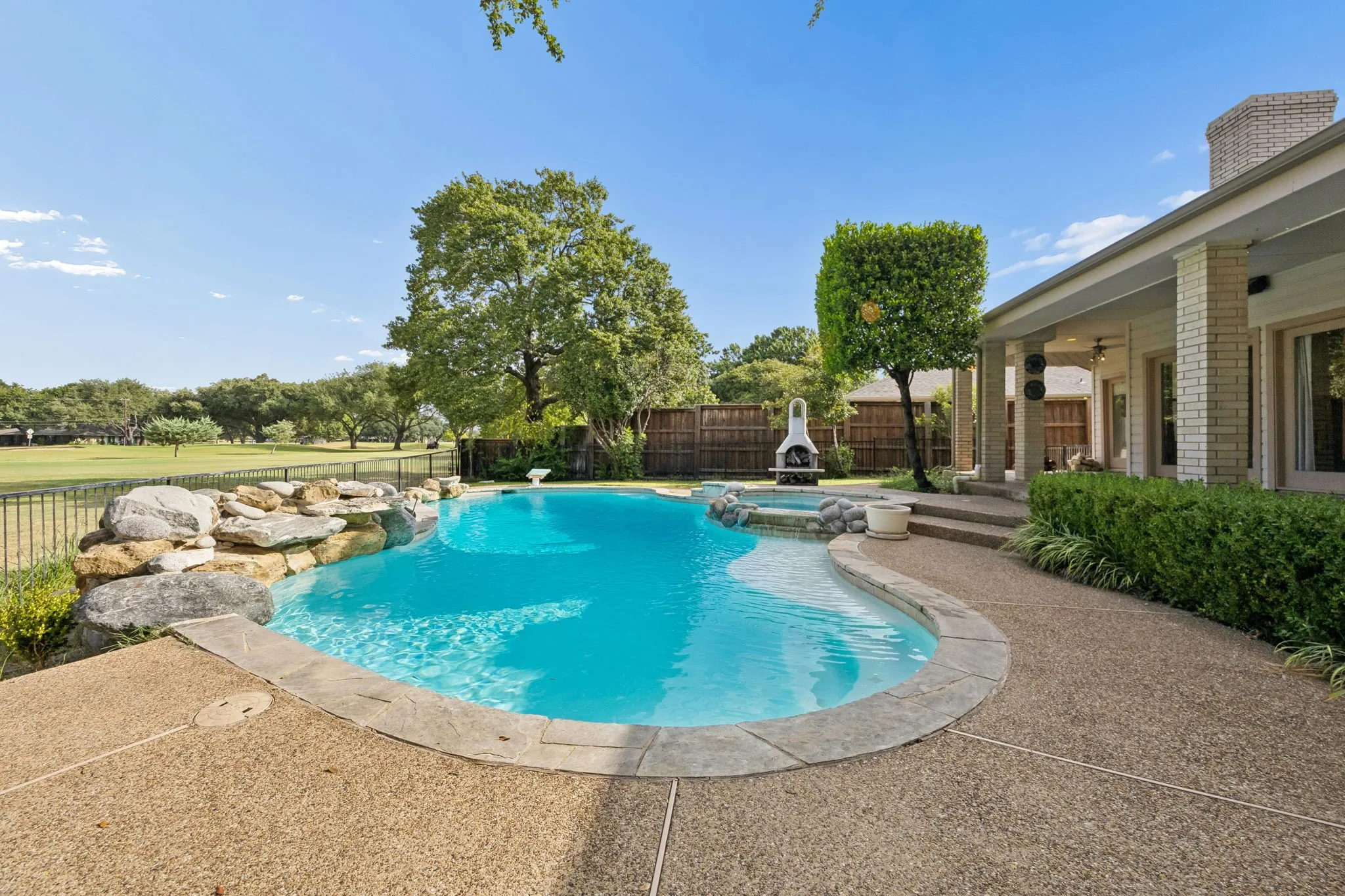 Expansive backyard featuring a freeform swimming pool, integrated spa, and rock waterfall