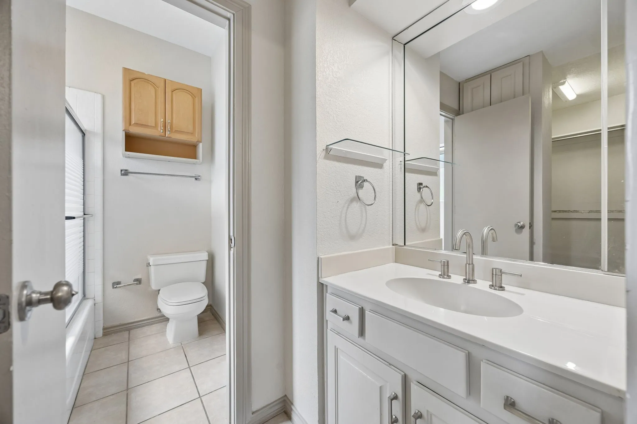 White vanity with an integrated sink, brushed nickel faucet, and a large wall-mounted mirror