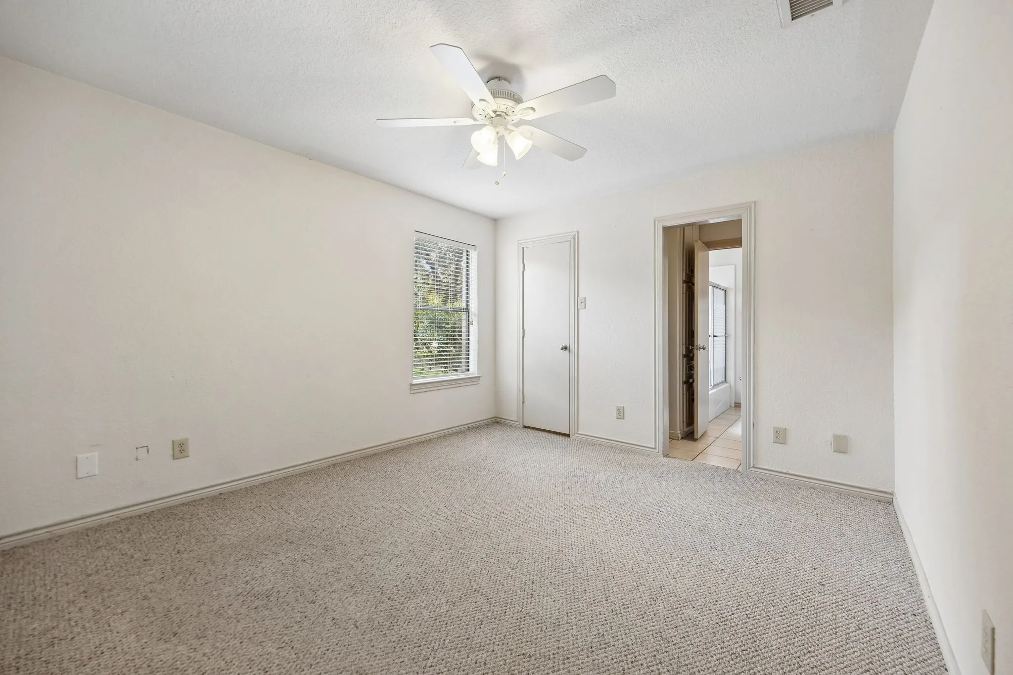 Carpeted room featuring a ceiling fan, a window with blinds, and white painted walls