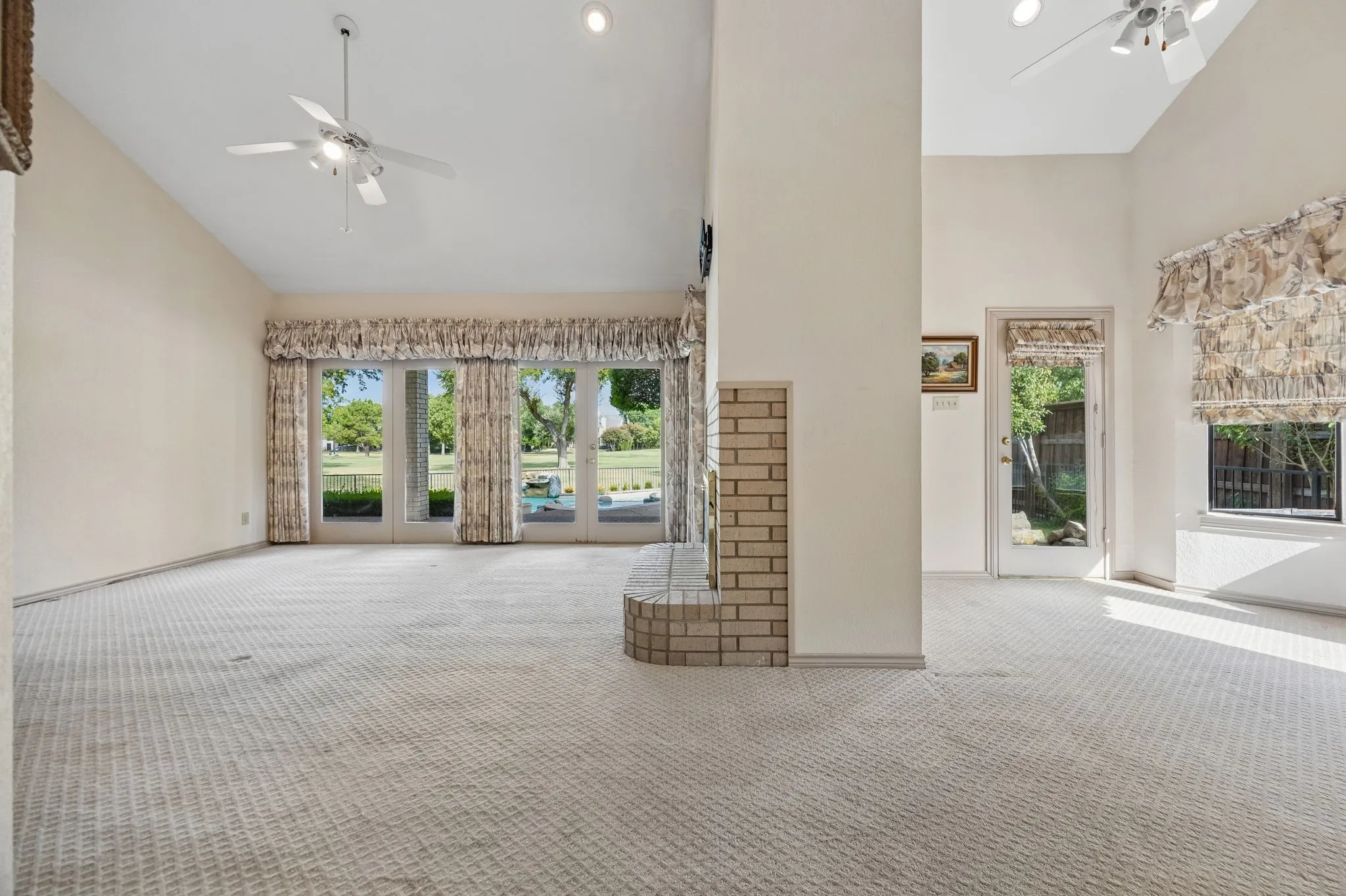 Vaulted ceilings, brick fireplace, glass paneled doors, and ceiling fans
