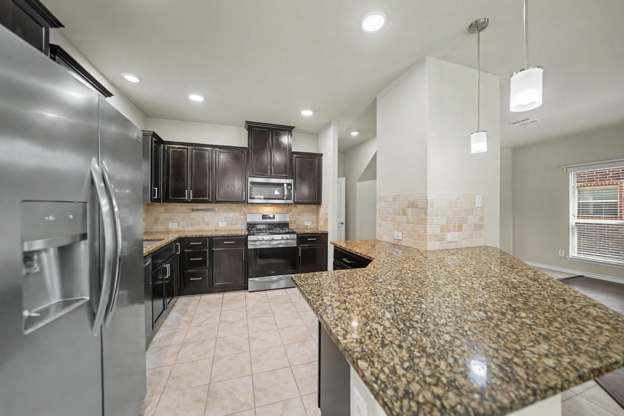 Kitchen featuring granite countertops, wood cabinetry, stainless steel appliances, tile flooring, and recessed lighting