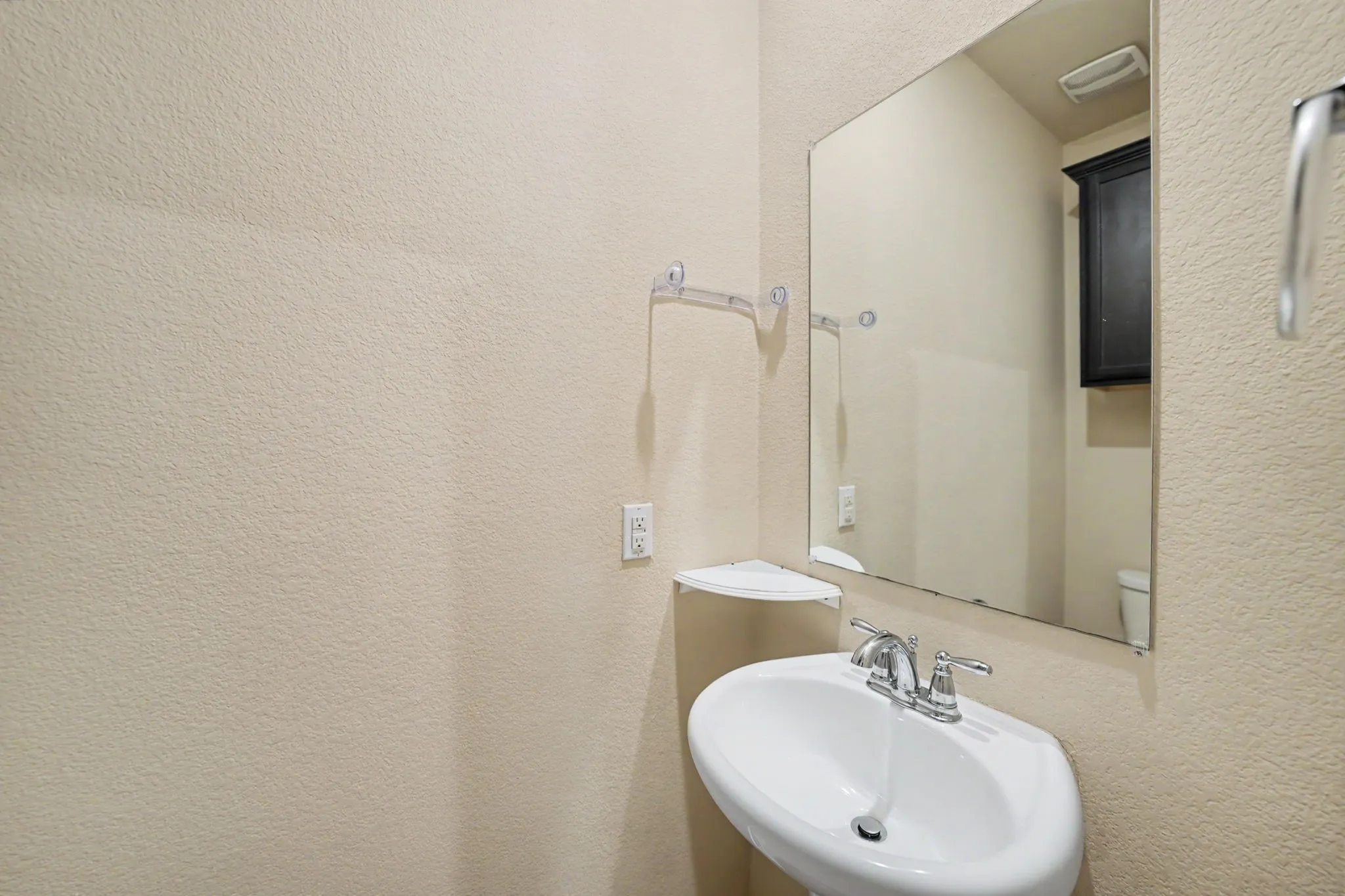 Pedestal sink with chrome fixtures and a wall-mounted mirror