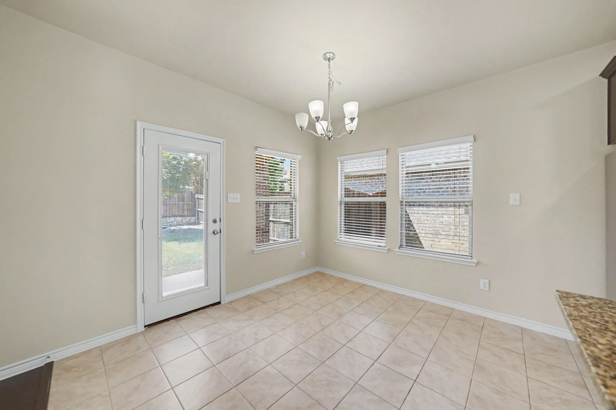 Ceramic tile flooring, multiple windows, glass-paneled exterior door, and a multi-light chandelier
