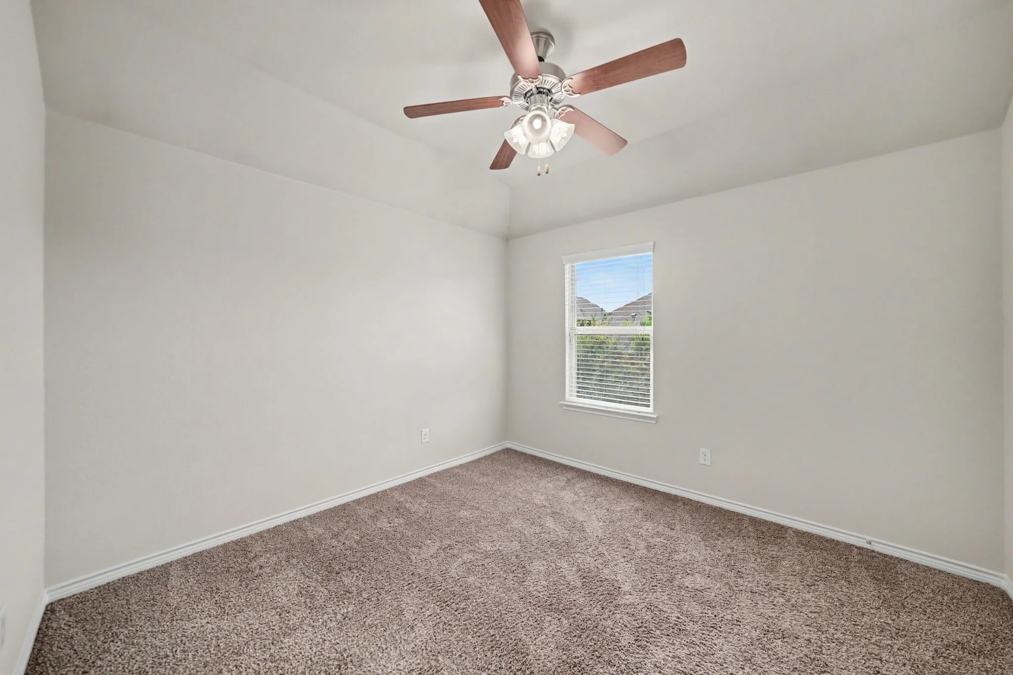 Vaulted ceiling, ceiling fan with integrated lighting, single-pane window with blinds, and neutral-toned carpeting