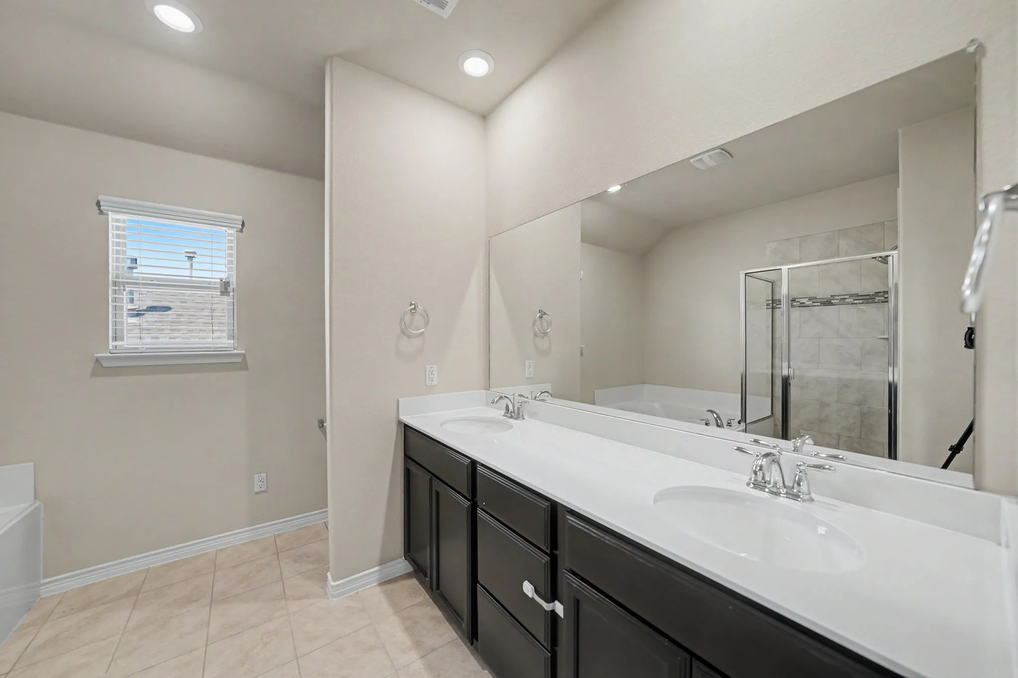 Dual vanity with white countertops, dark wood-finish cabinetry, and an expansive mirror