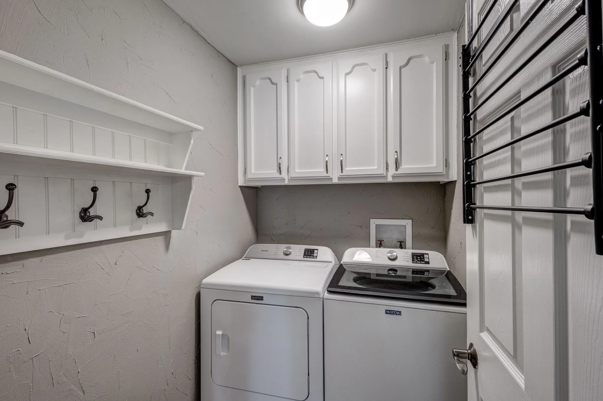 Built-in storage shelf with hooks, white cabinetry, and overhead lighting